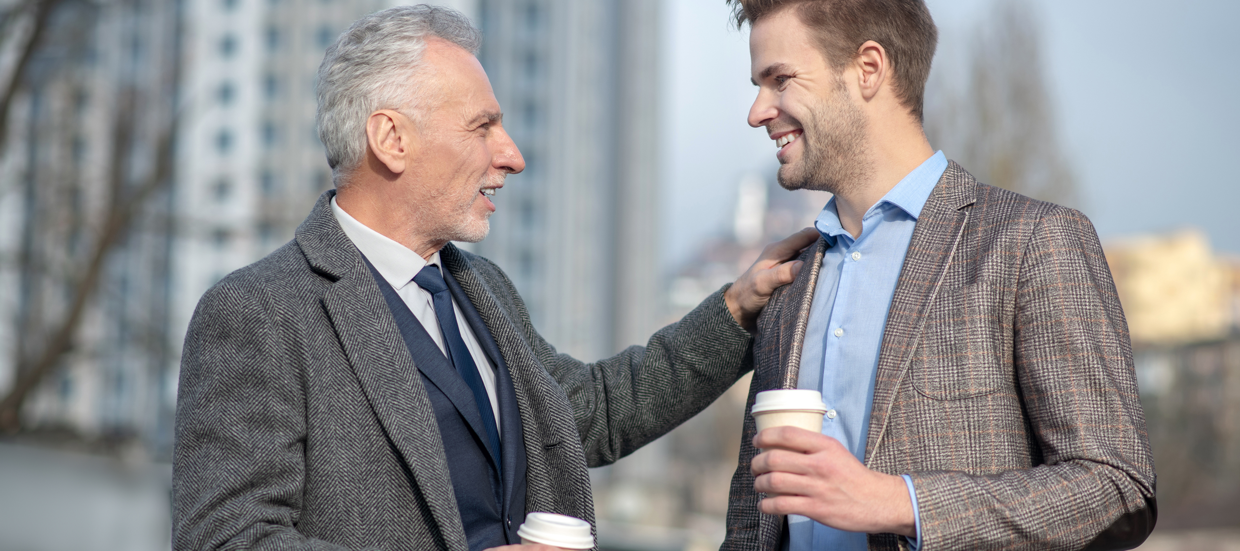 An older gentleman has a supportive conversation with a younger man about a nondescript topic.
