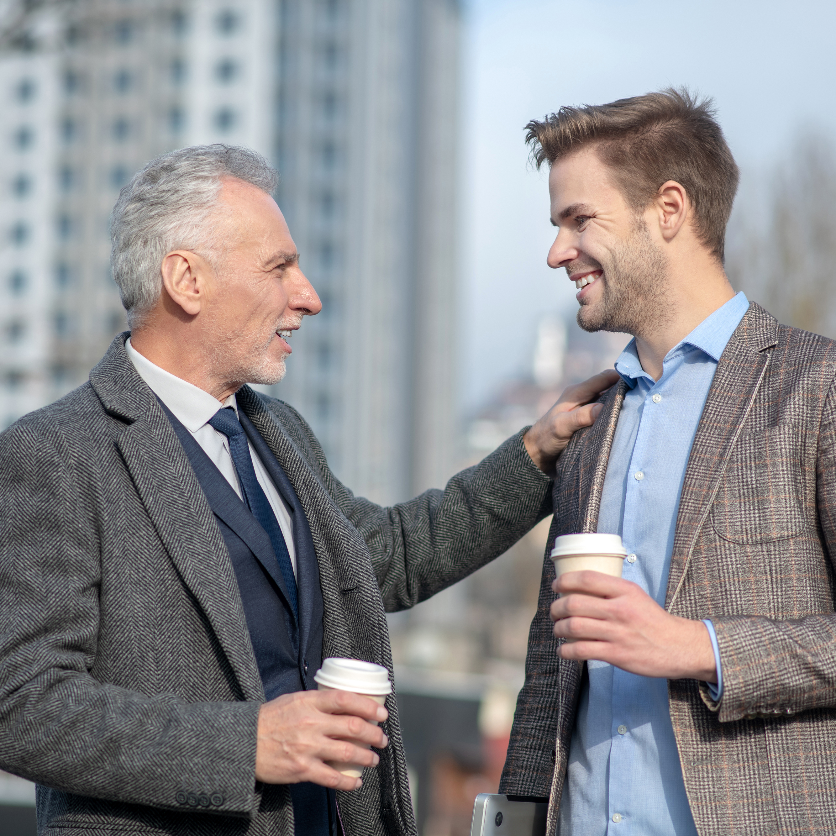An older gentleman has a supportive conversation with a younger man about a nondescript topic.