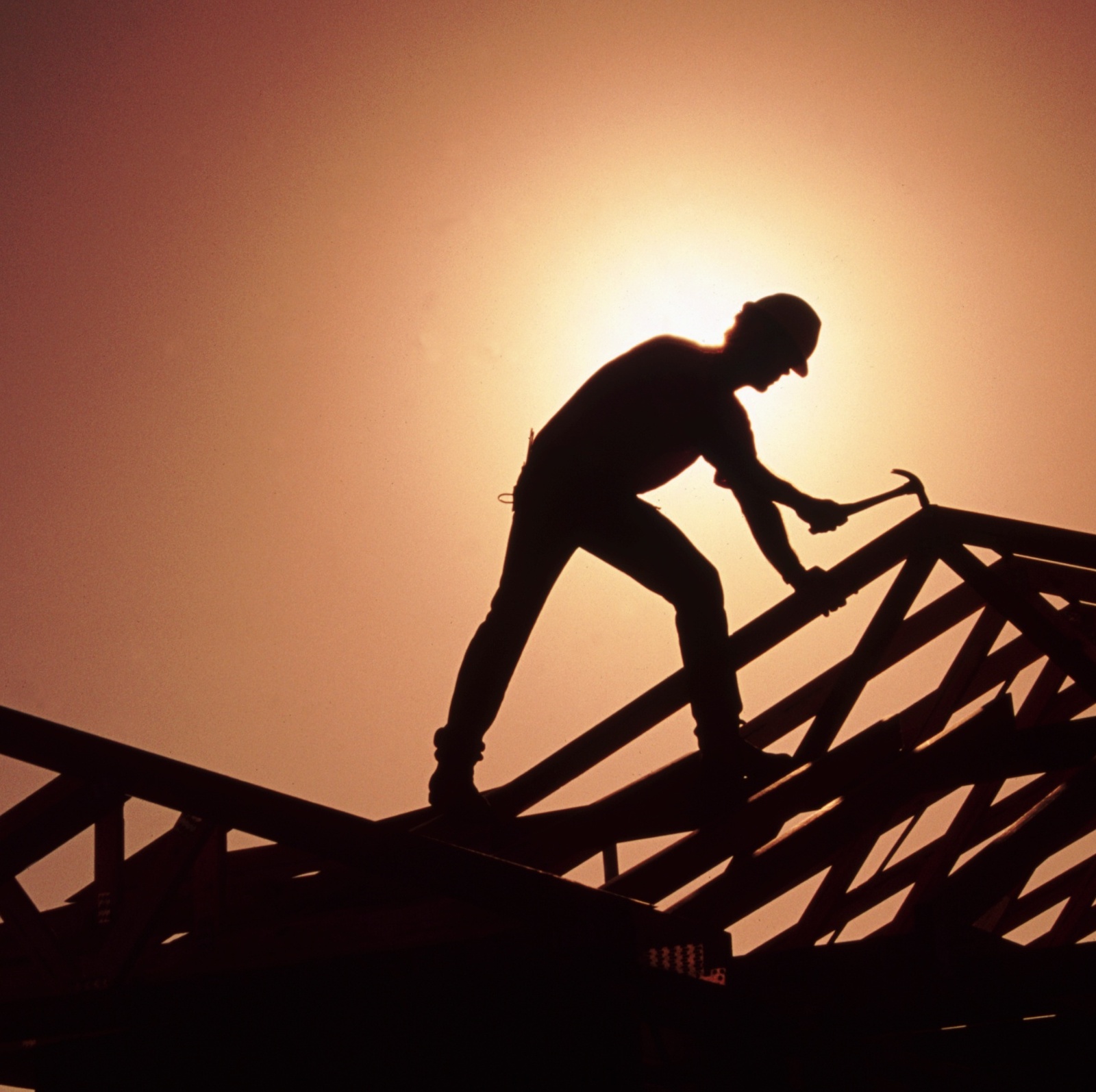 A silhouette of a homebuilder working on a roof