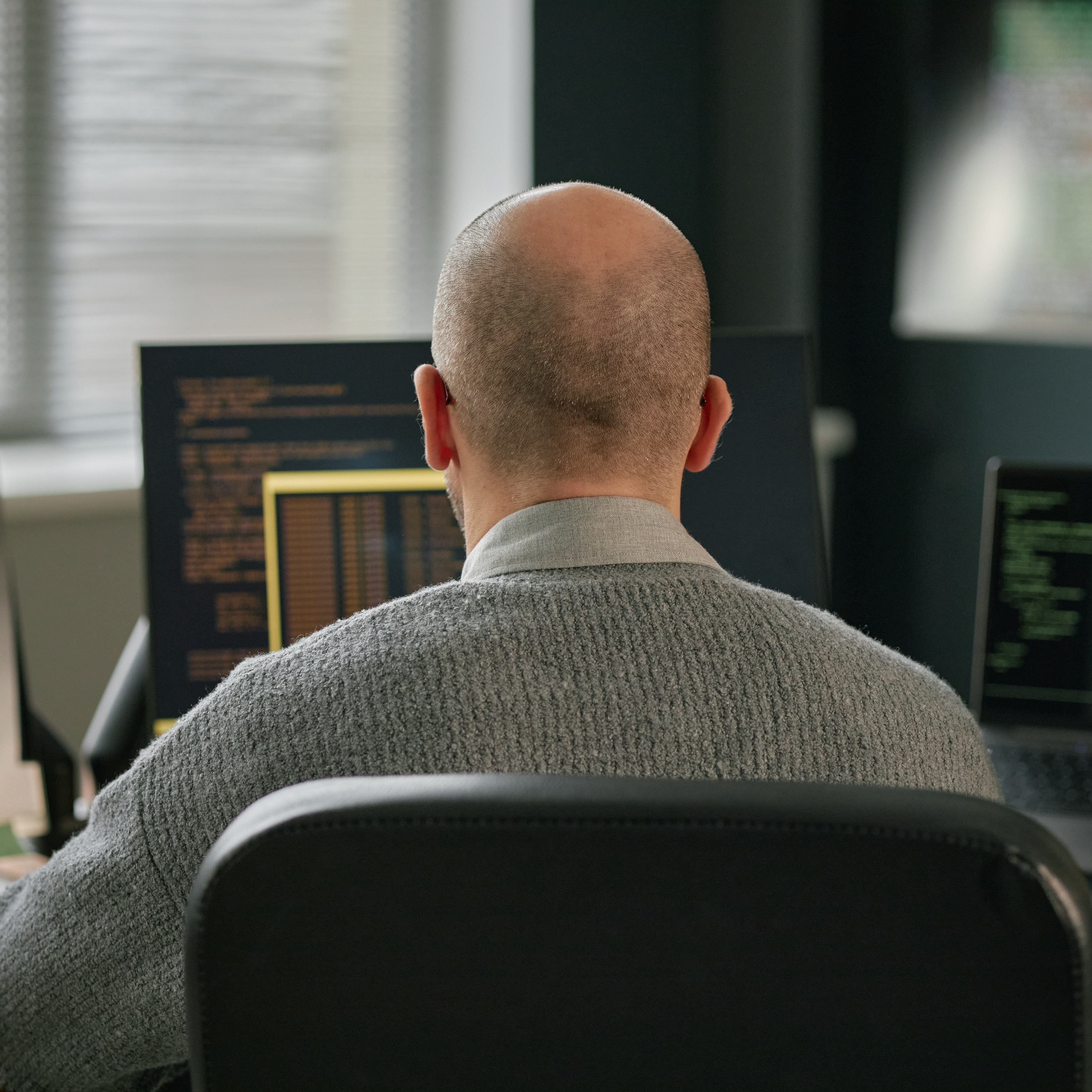 A man tends to his job using multiple computer screens.