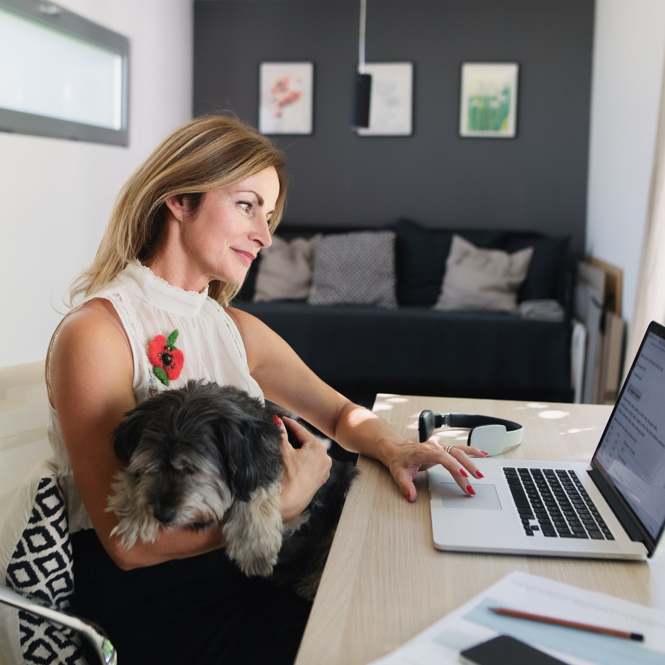 Woman working from home at desk with dog in her lap