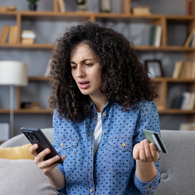 Woman feeling frustrated and confused while looking at her credit card bill.