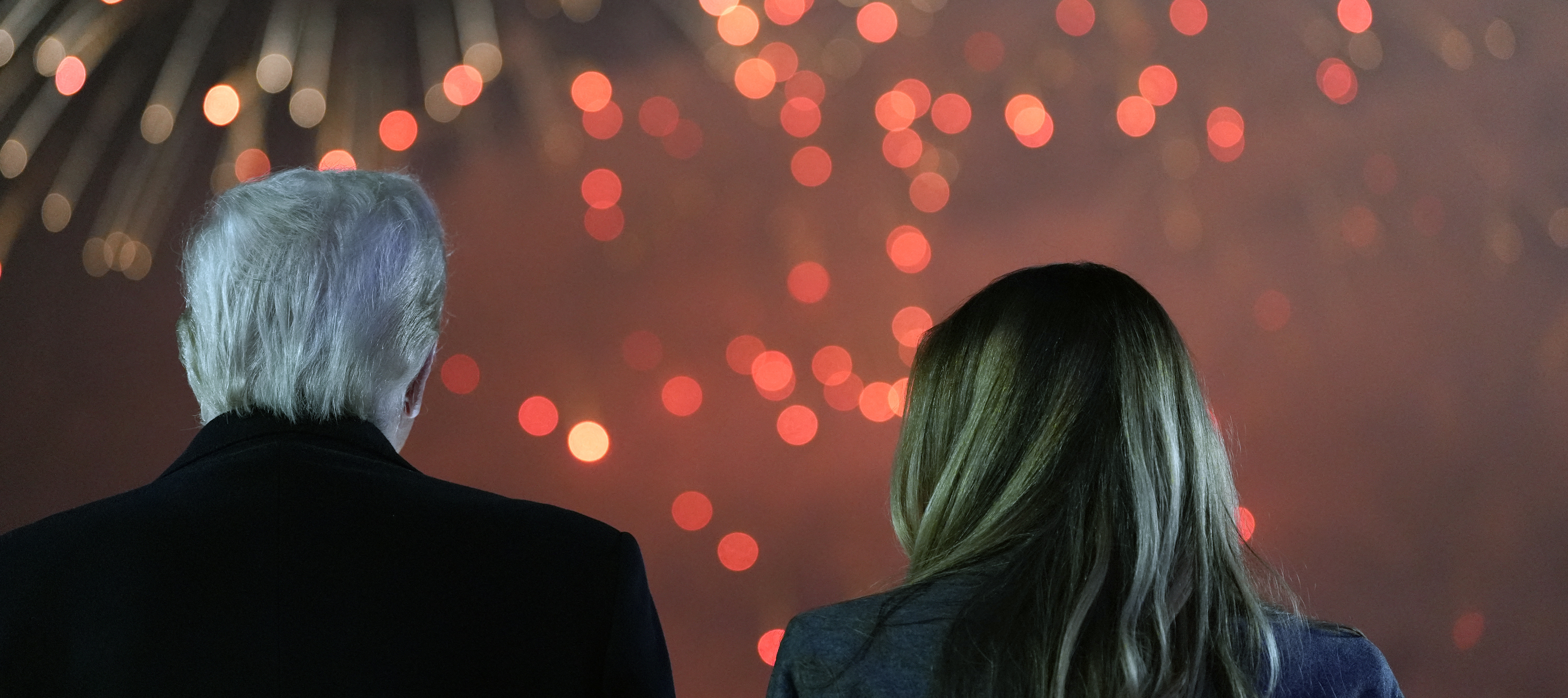 Donald Trump and his wife Melania Trump stand to watch fireworks during a reception in his honor.