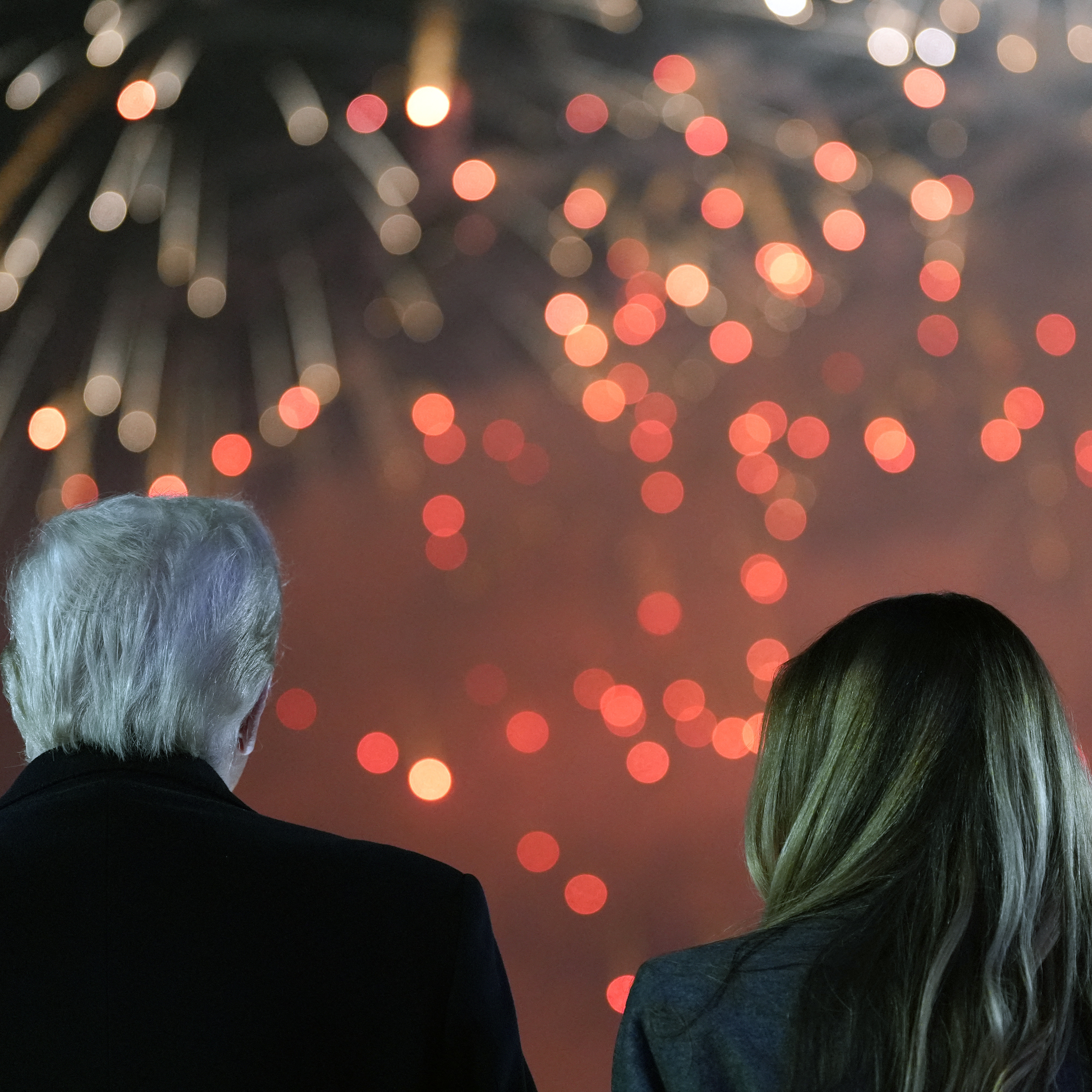 Donald Trump and his wife Melania Trump stand to watch fireworks during a reception in his honor.