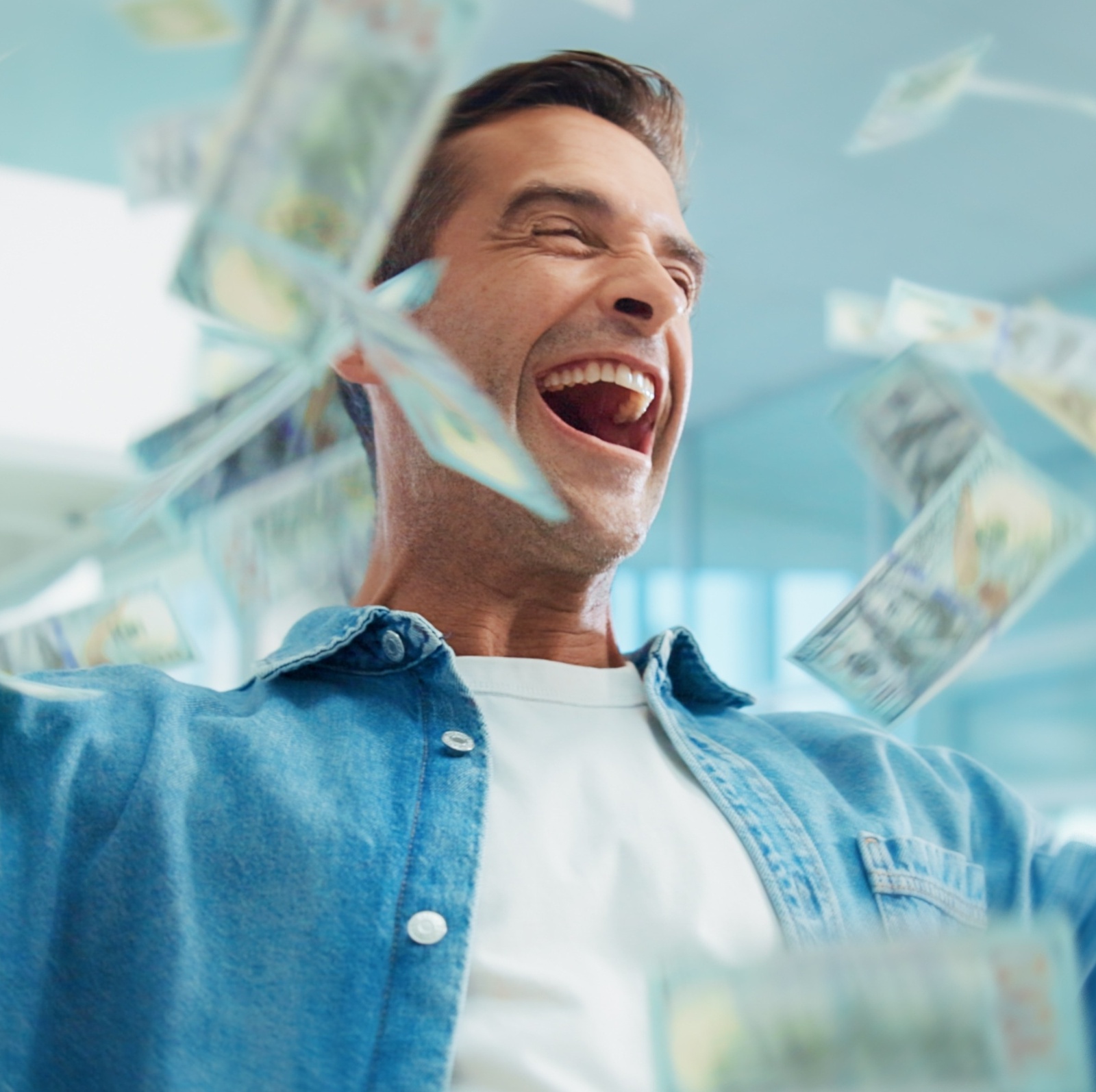 A man celebrating with his hands in the air as money flies around him