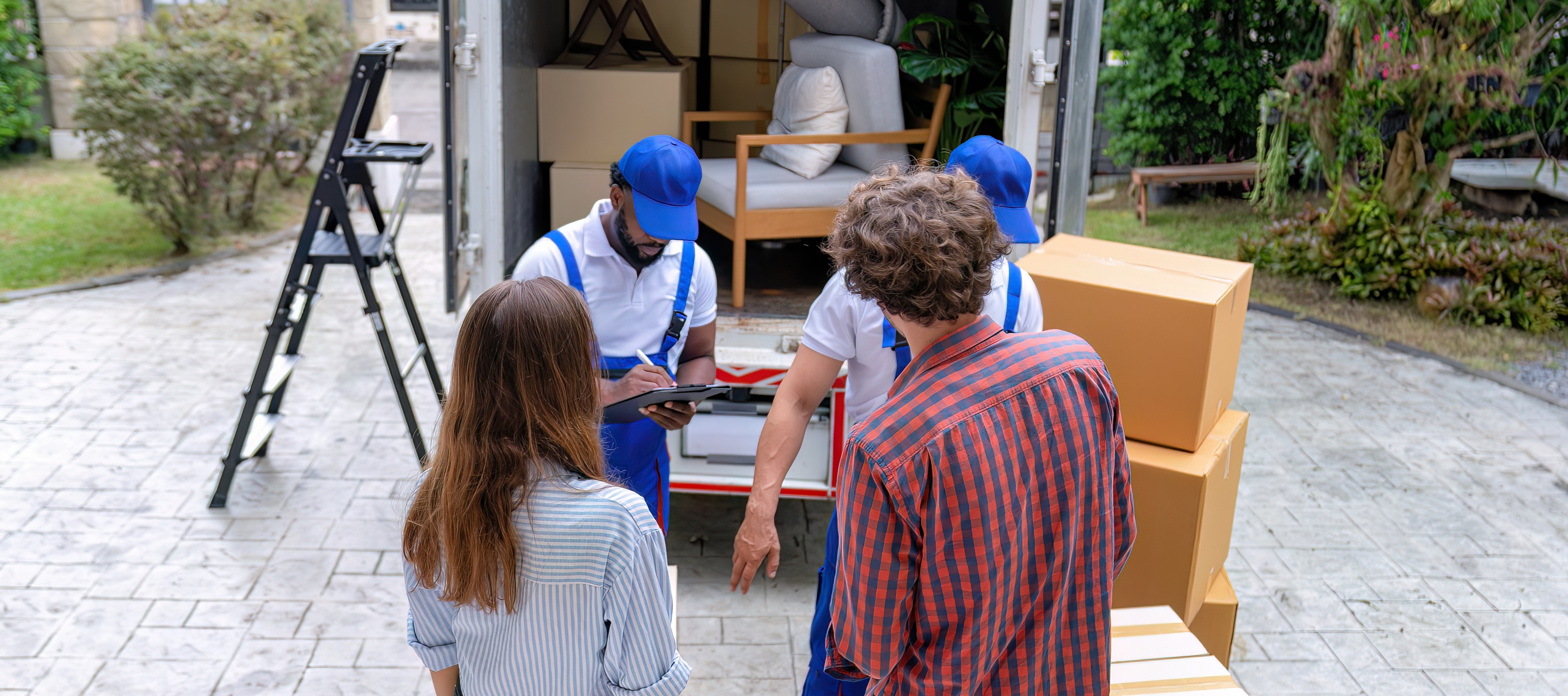 Young couple watching movers pack their stuff into truck