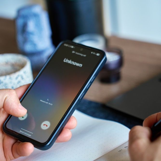 A photo of a phone ringing with a call from an unknown number