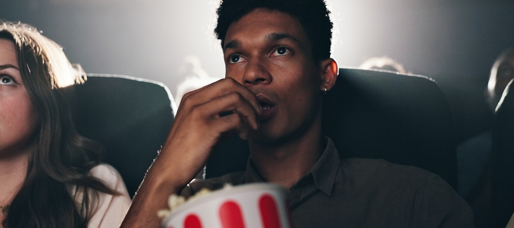 A photo of a man eating popcorn at a movie theater