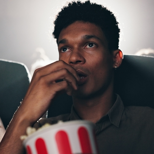 A photo of a man eating popcorn at a movie theater