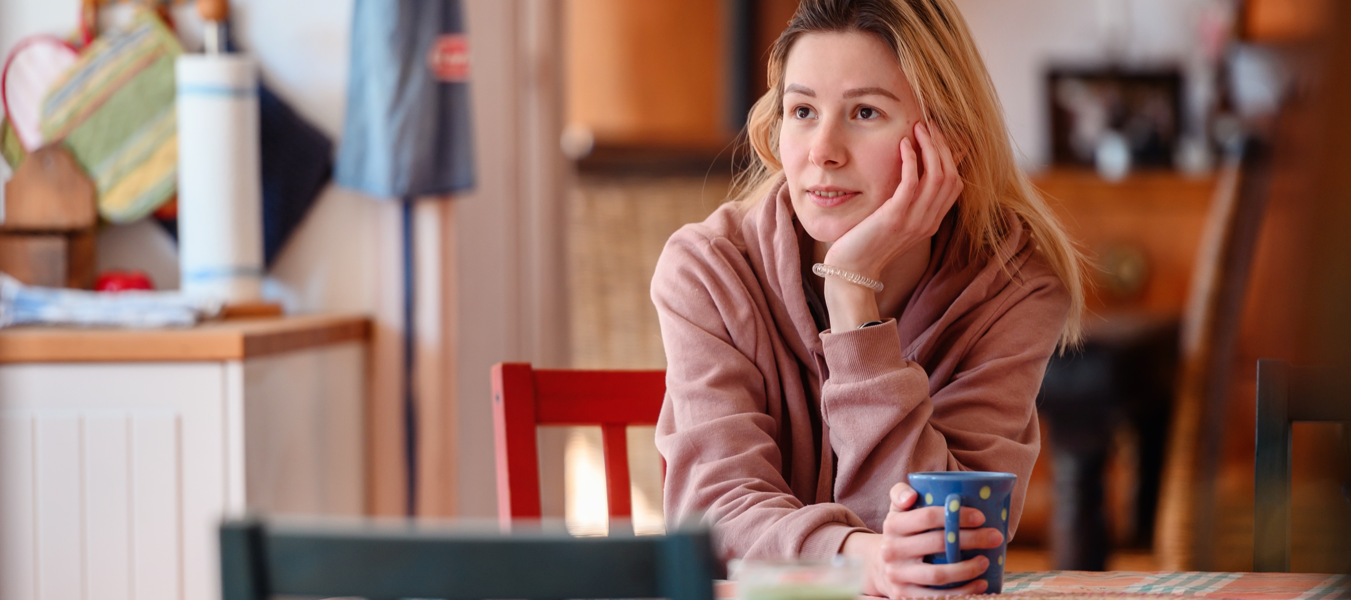 Young woman sipping tea at kitchen table