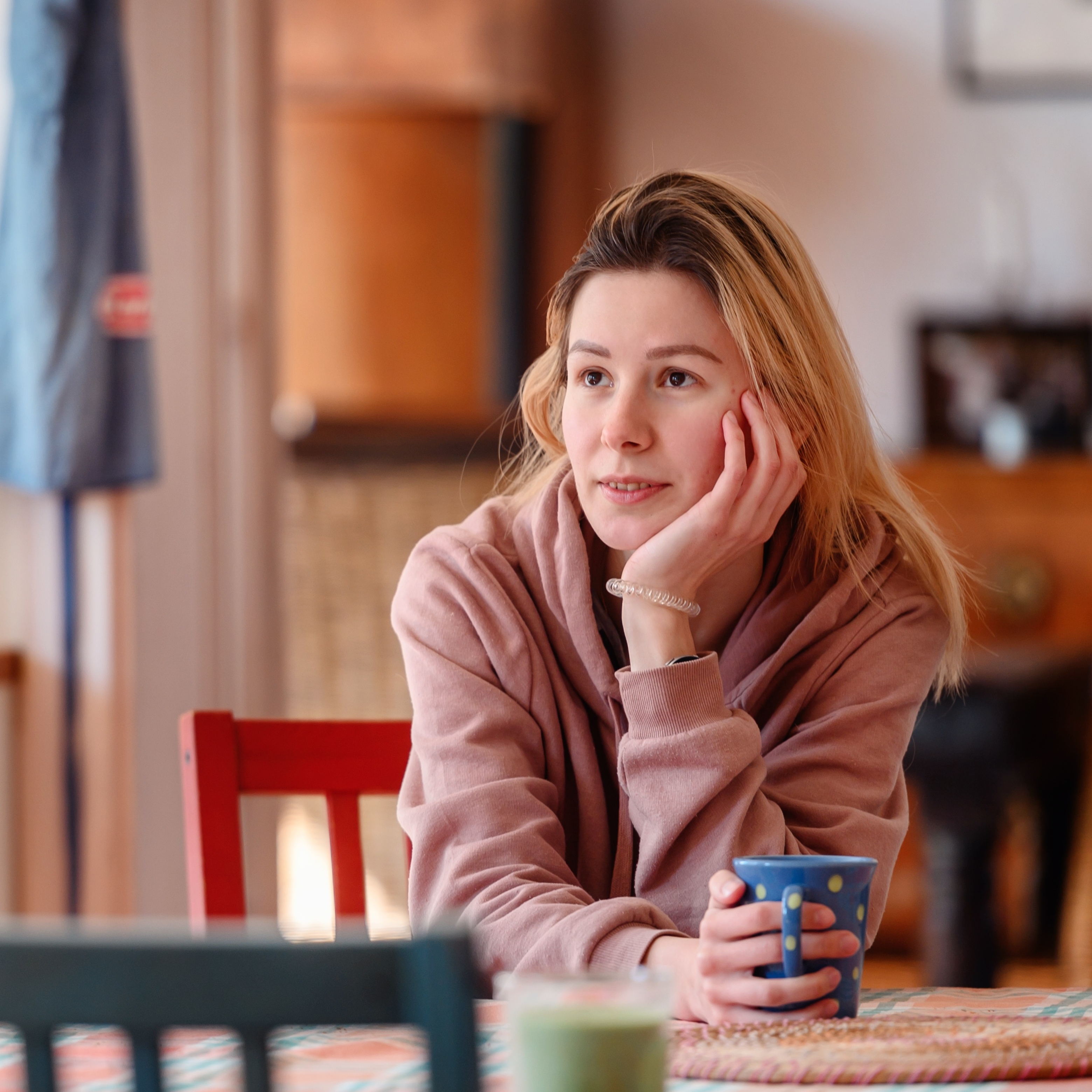 Young woman sipping tea at kitchen table