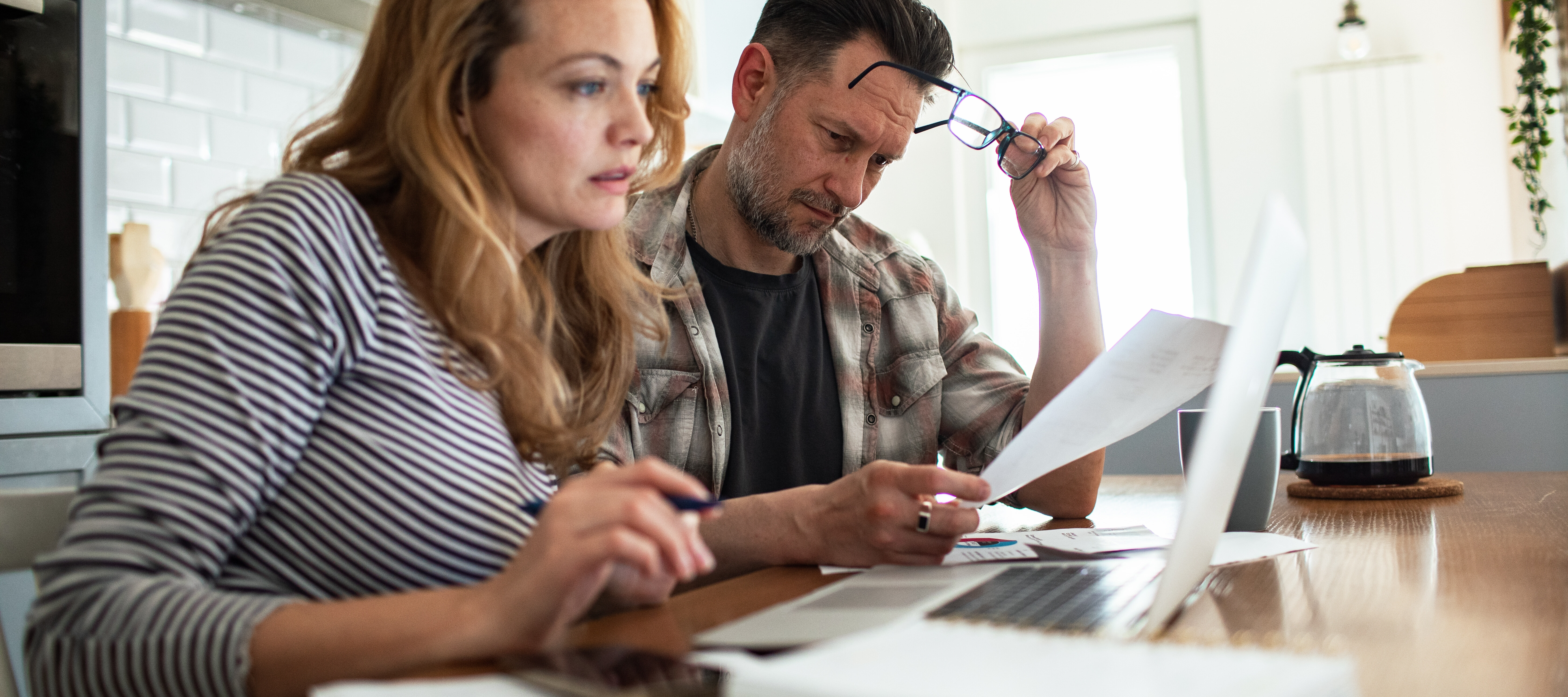A couple reviews bills together at the kitchen table.