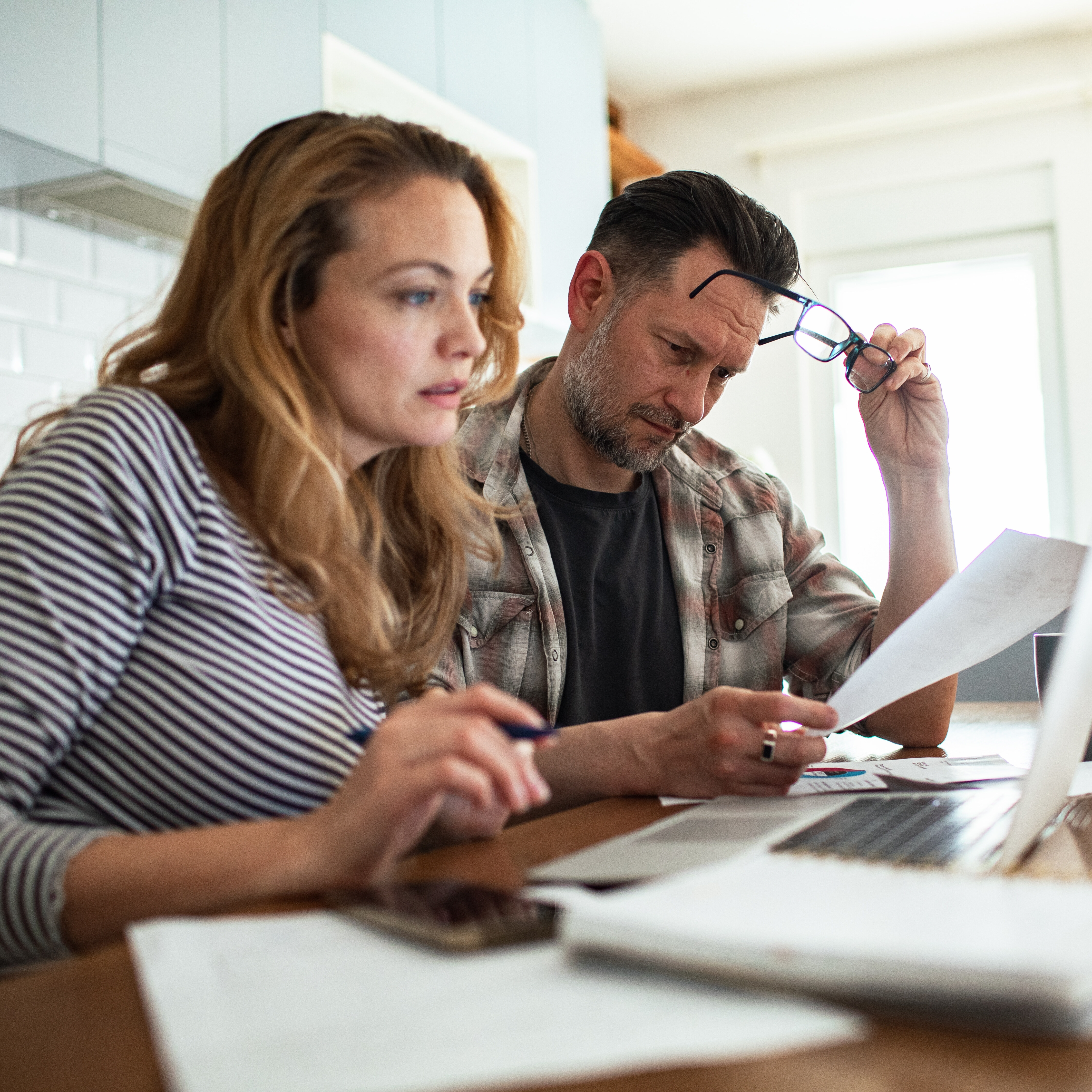 A couple reviews bills together at the kitchen table.