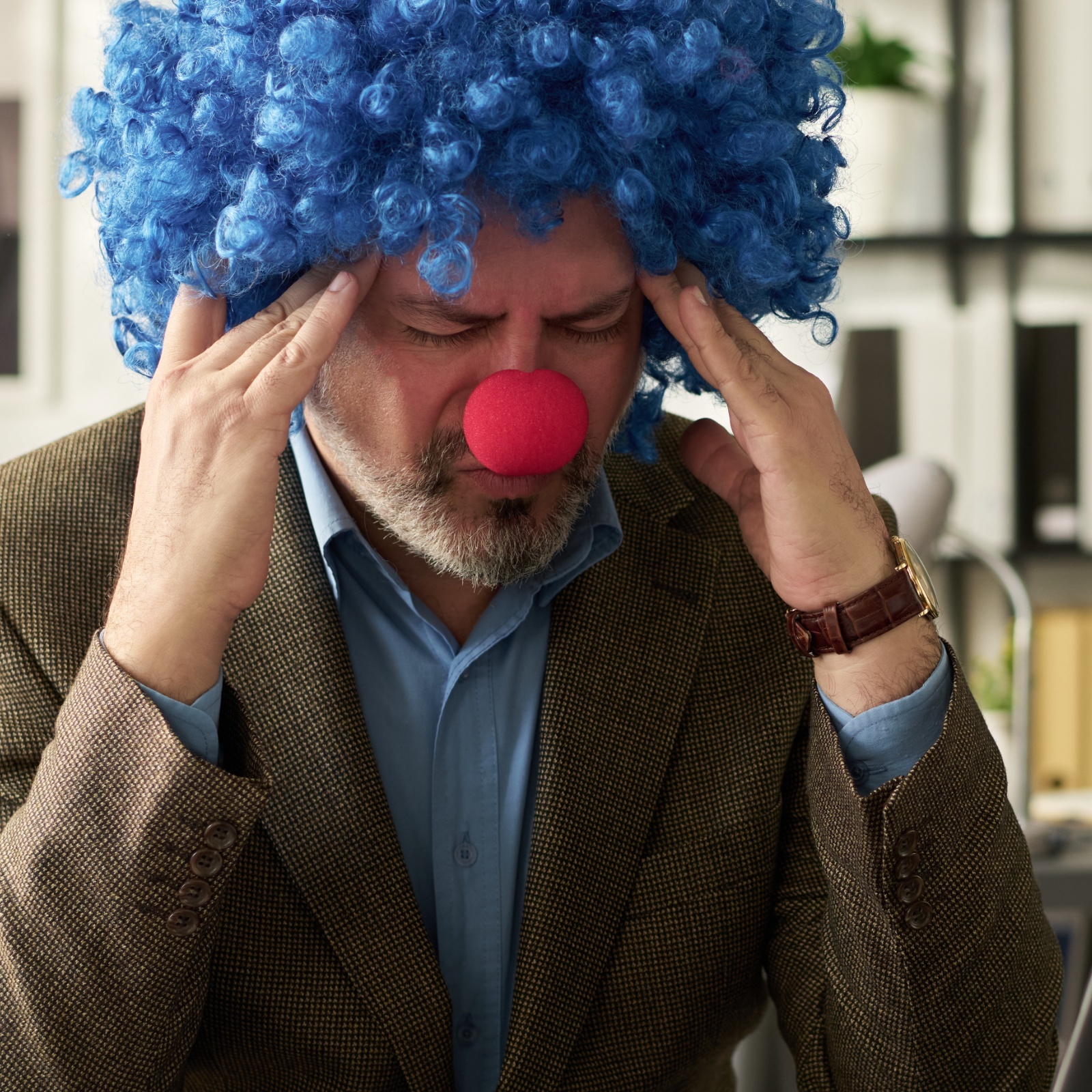 A worker who lost everything wearing a clown wig and nose at the office.