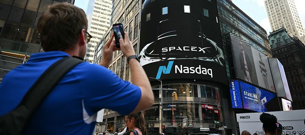 A photo of a person taking a picture of a SpaceX IPO announcement