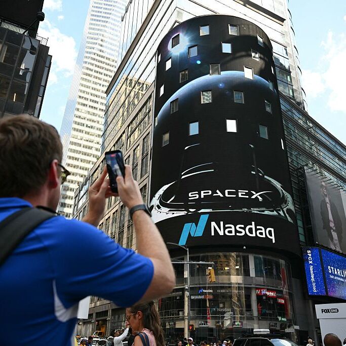 A photo of a person taking a picture of a SpaceX IPO announcement