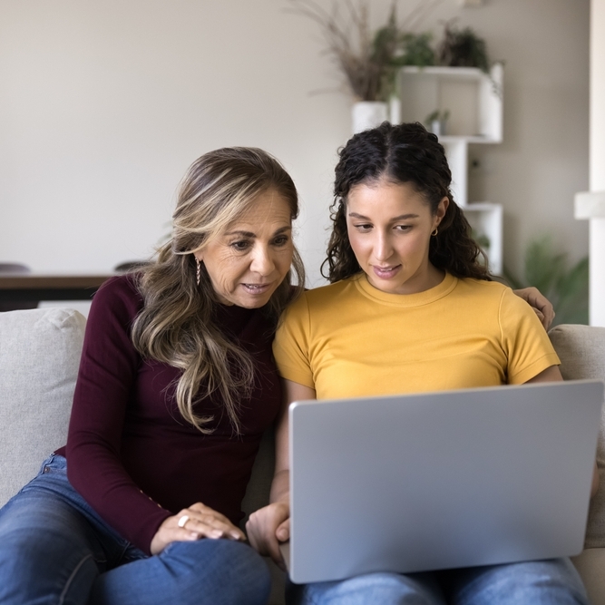 A daughter and a mother looking at a laptop