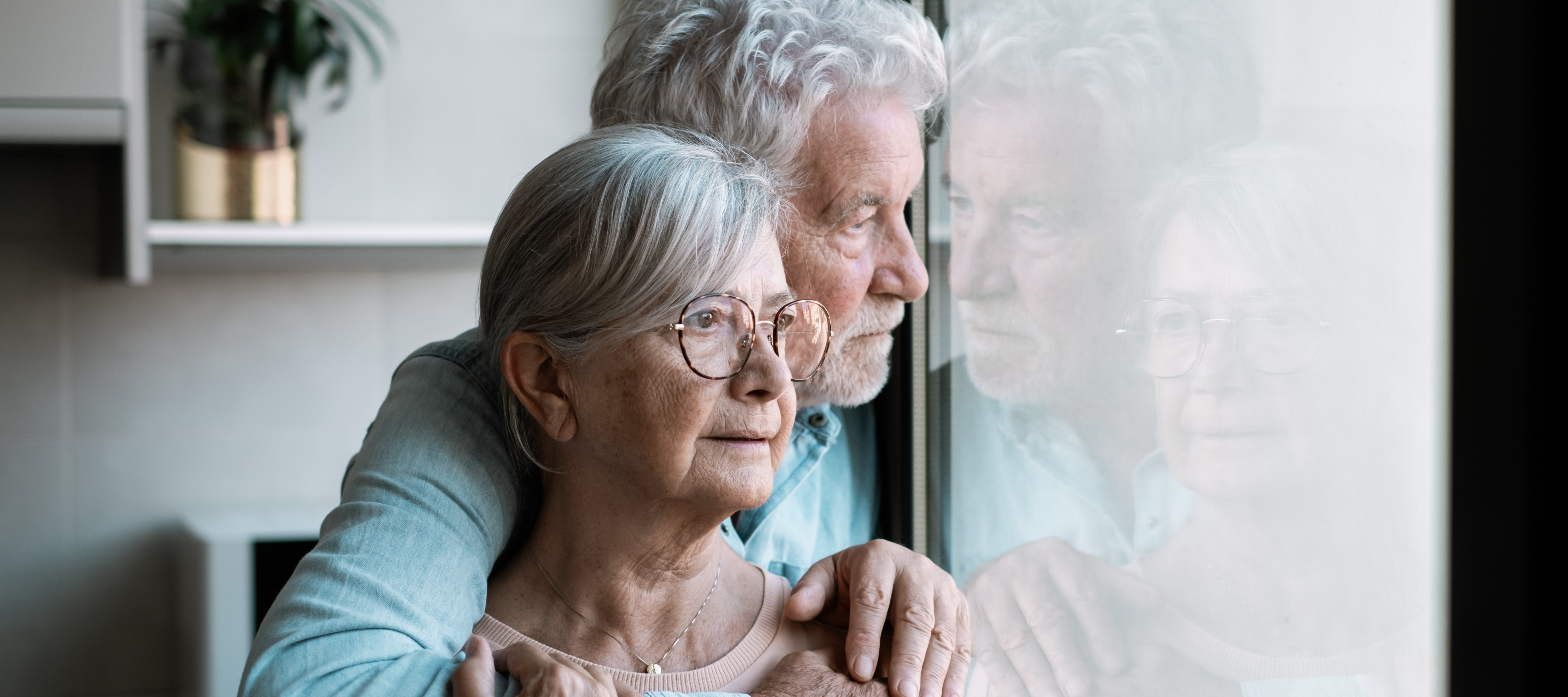 Couple looking out their window at home
