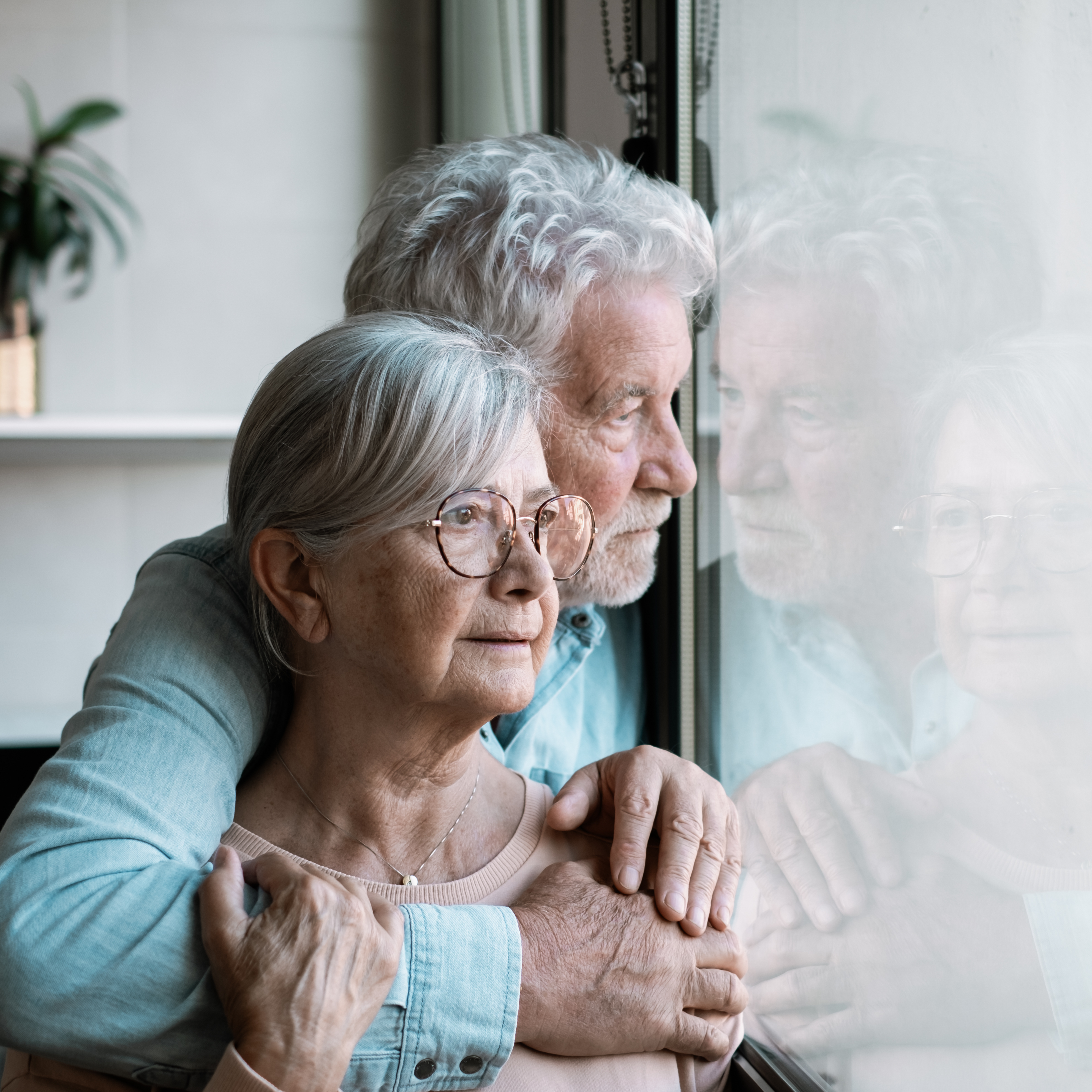 Couple looking out their window at home