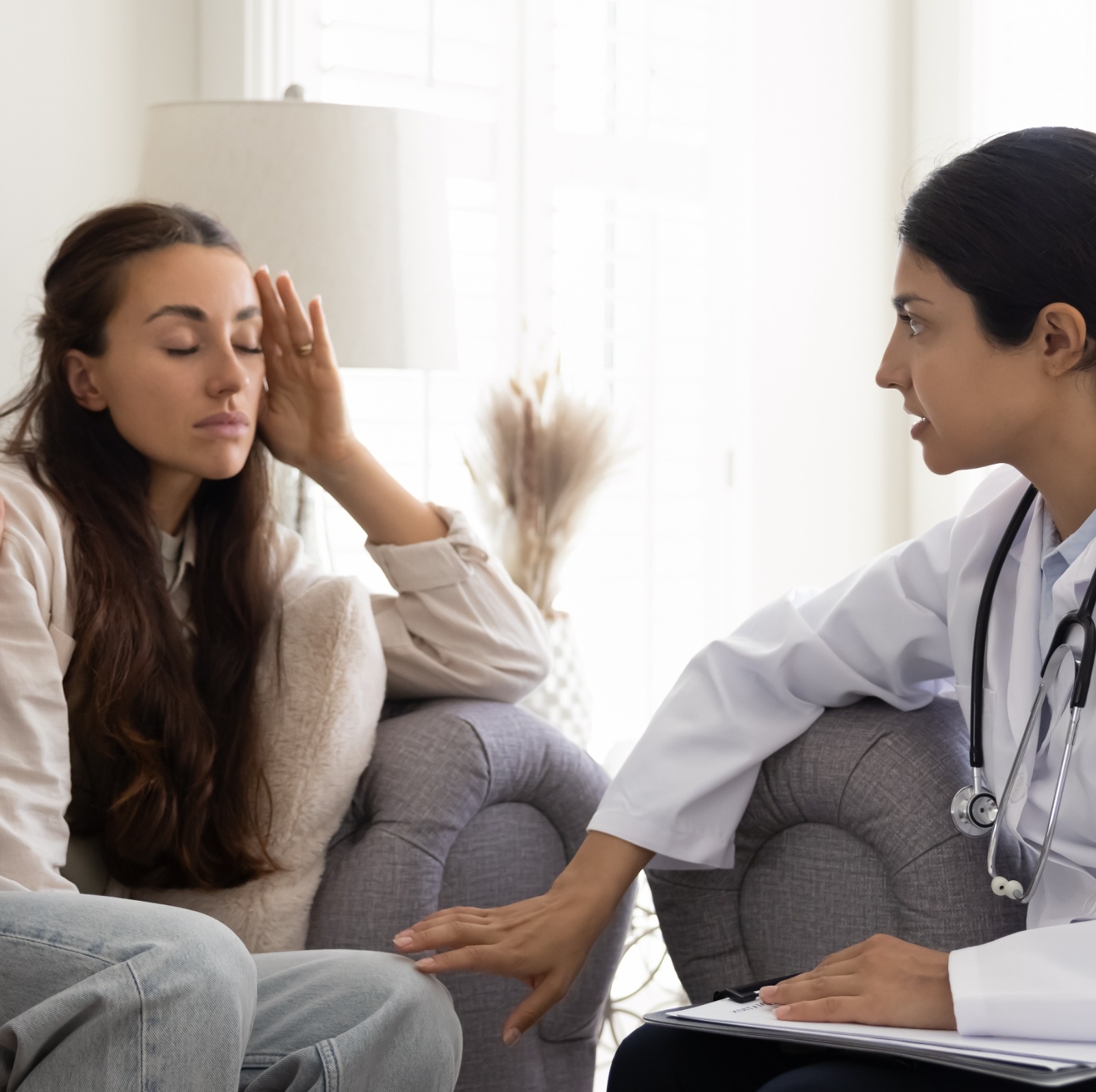 A man and a doctor console a worried-looking woman inside a doctor's office
