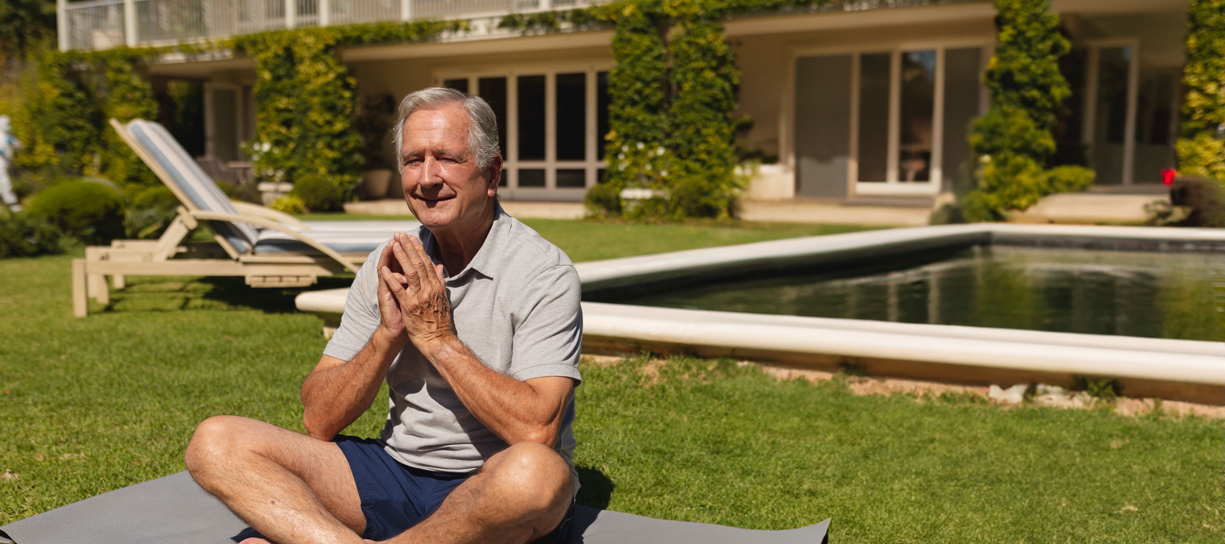older man sitting on yoga mat outside