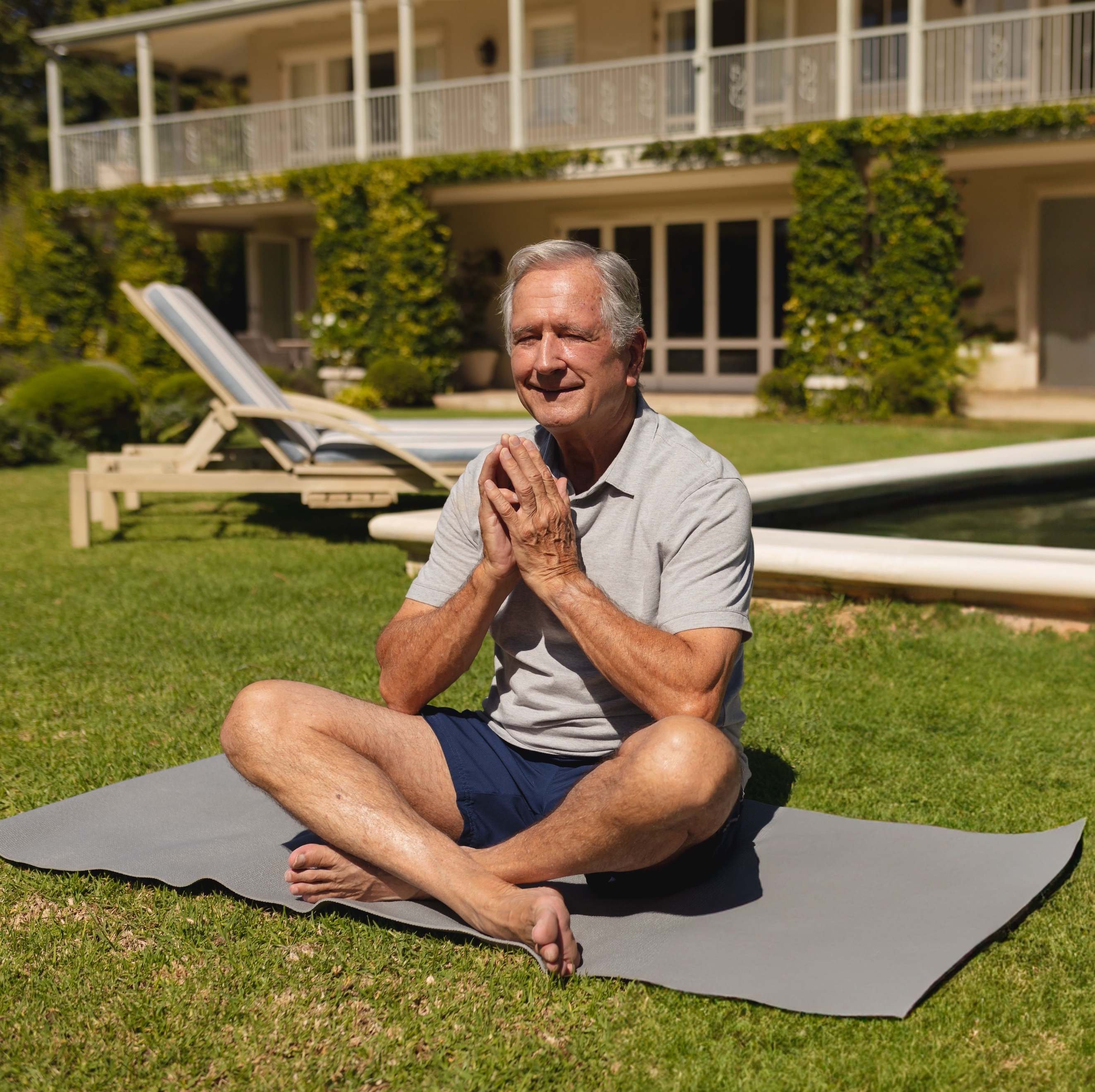 older man sitting on yoga mat outside