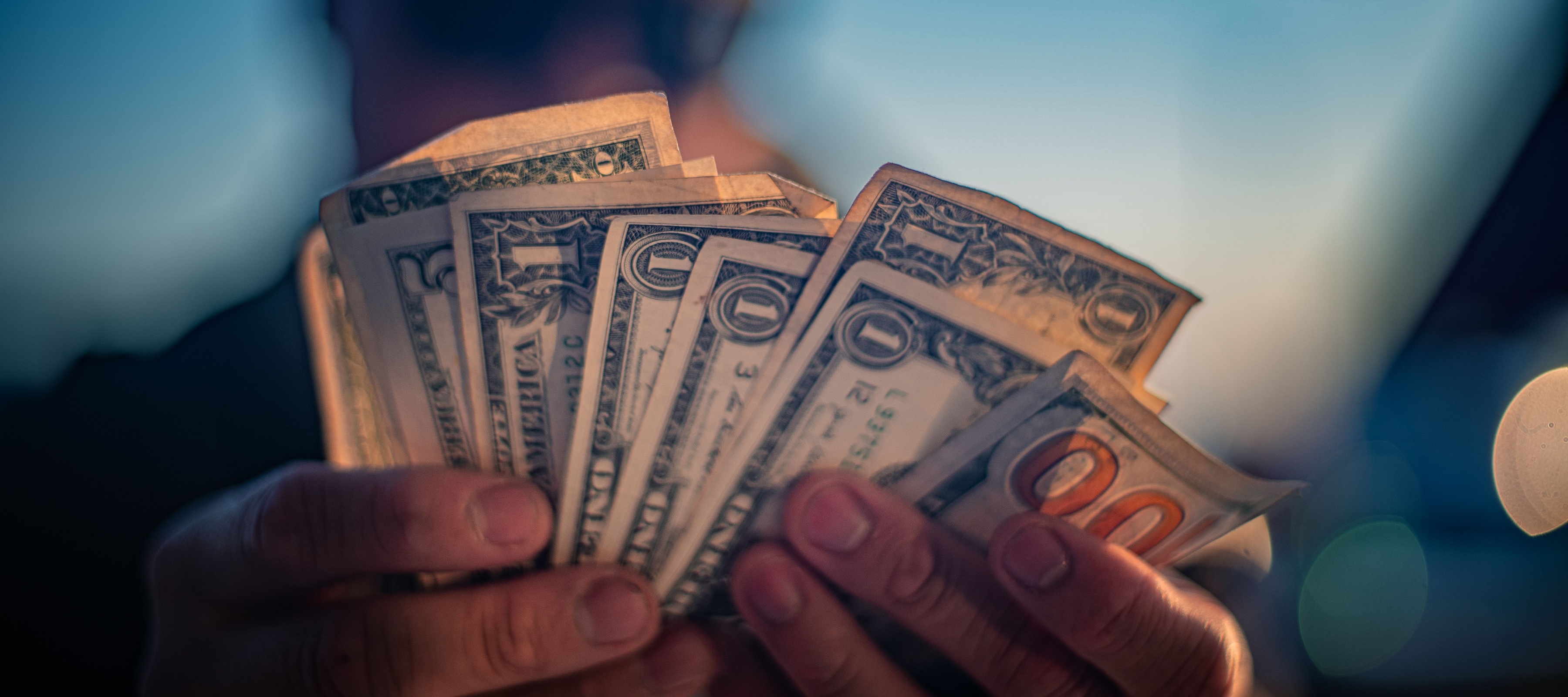 Close up of man holding fanned stack of U.S. cash.