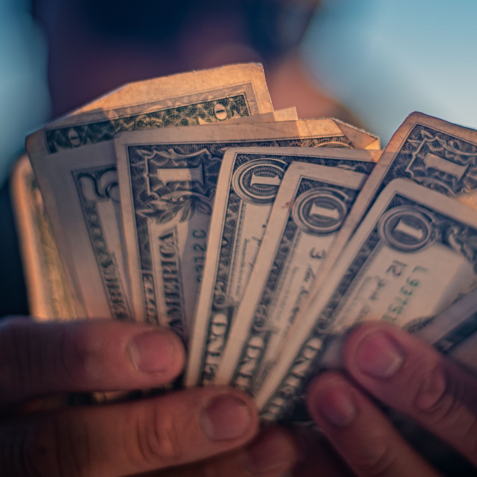 Close up of man holding fanned stack of U.S. cash.