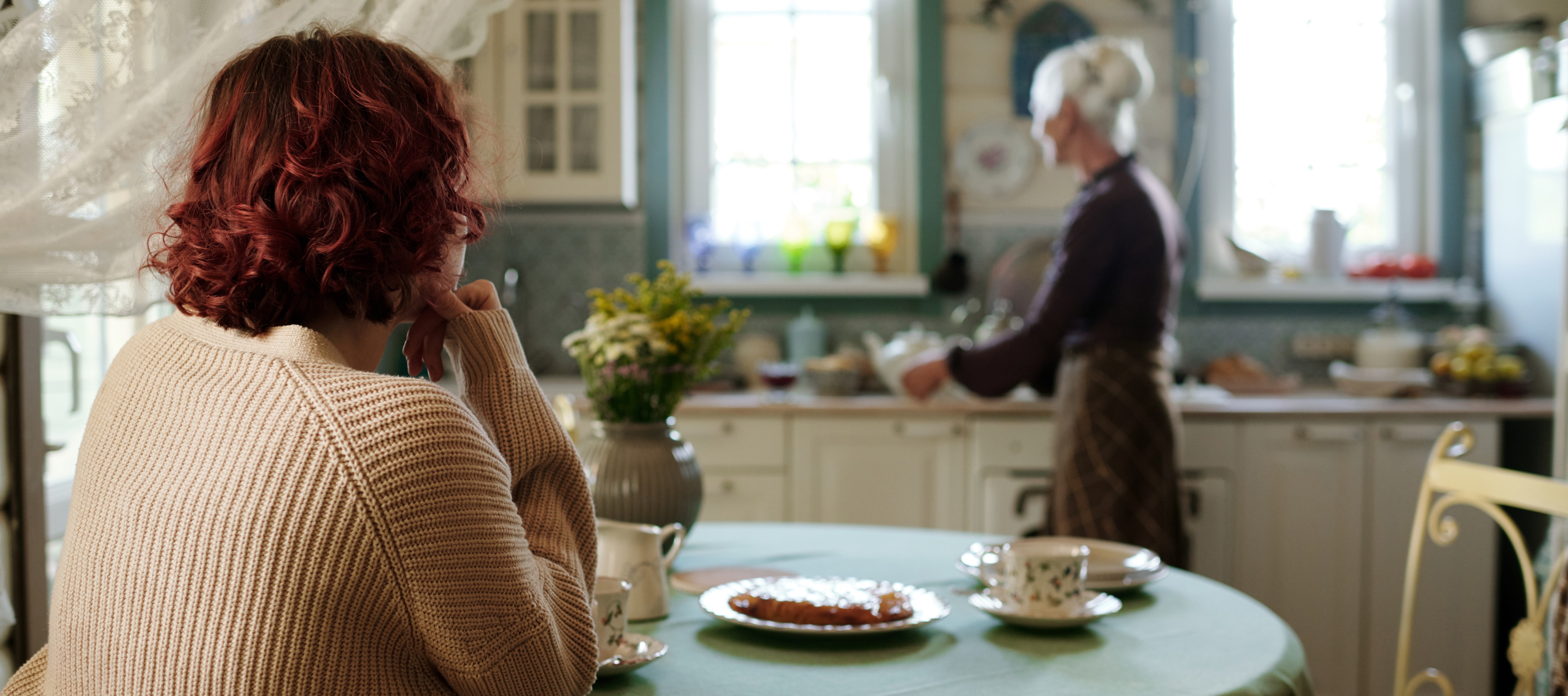 middle-aged women looking at senior woman in kitchen