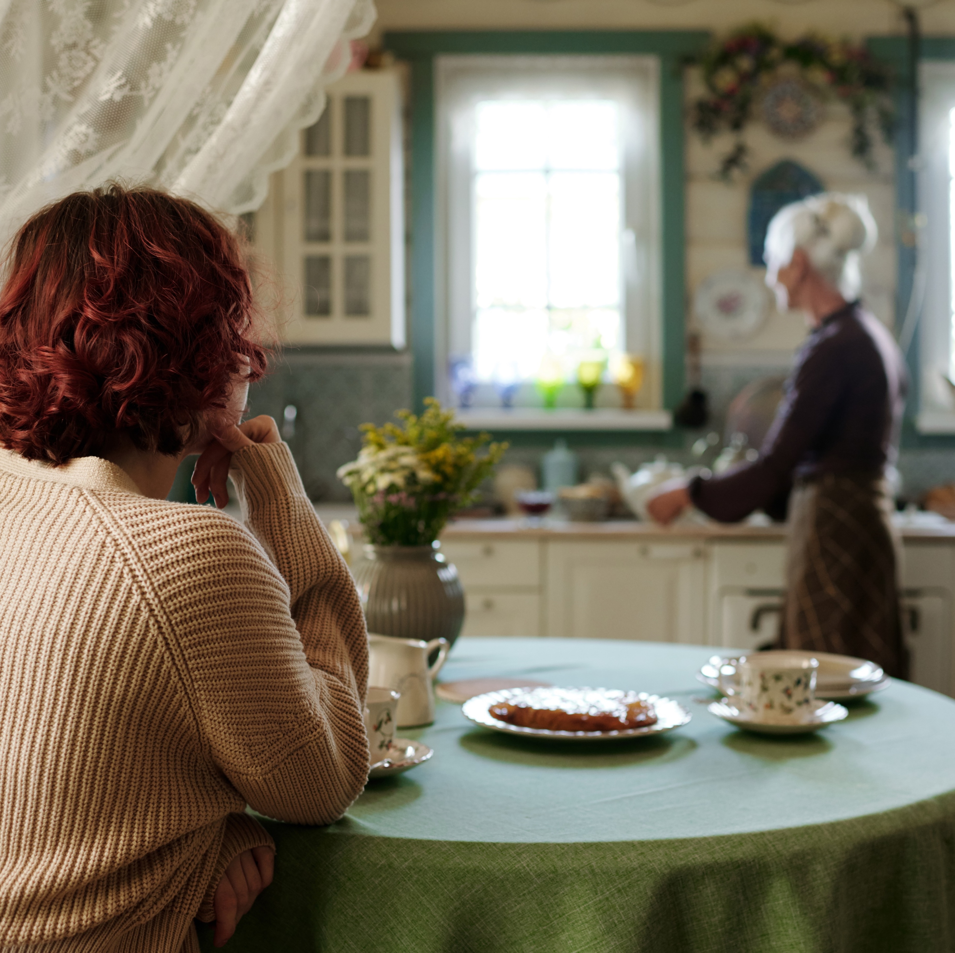 middle-aged women looking at senior woman in kitchen