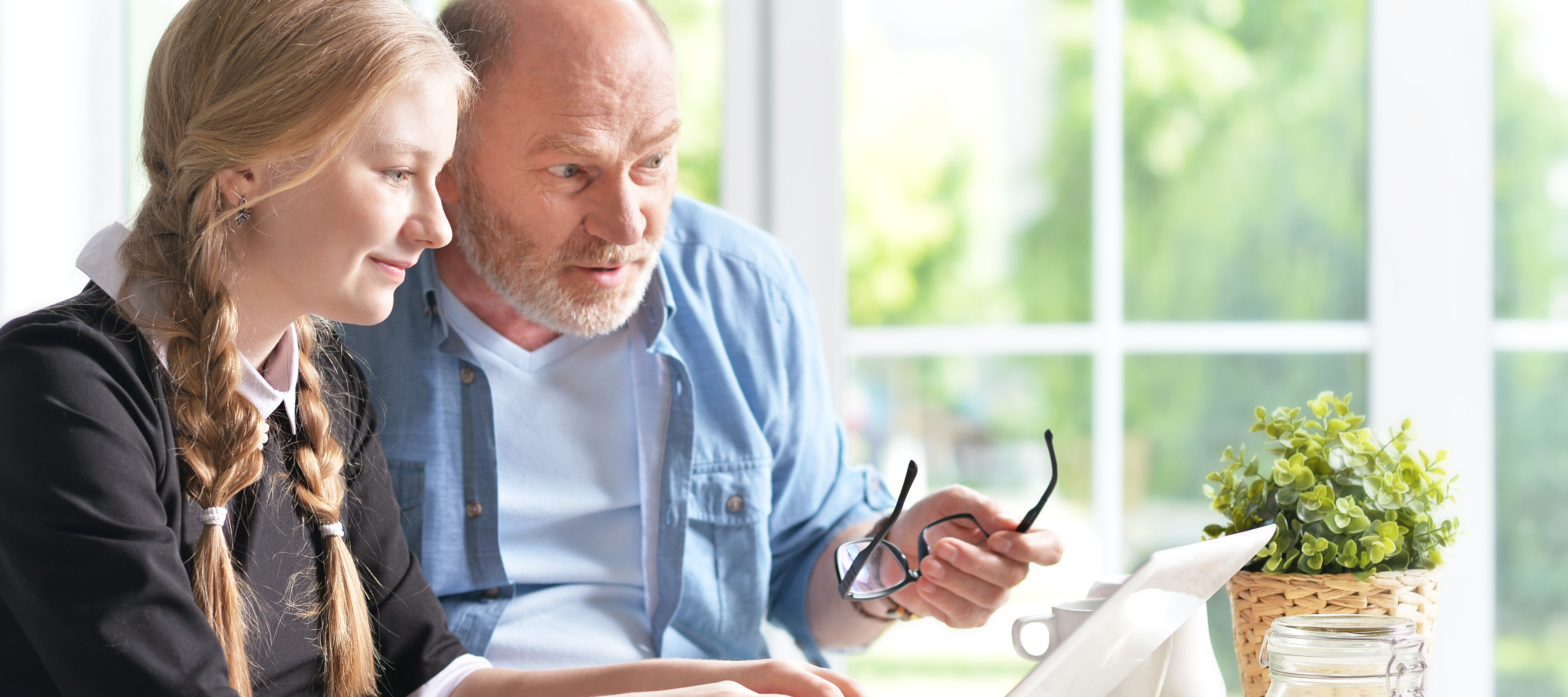 A grandfather sits with his granddaughter to go over her university application.