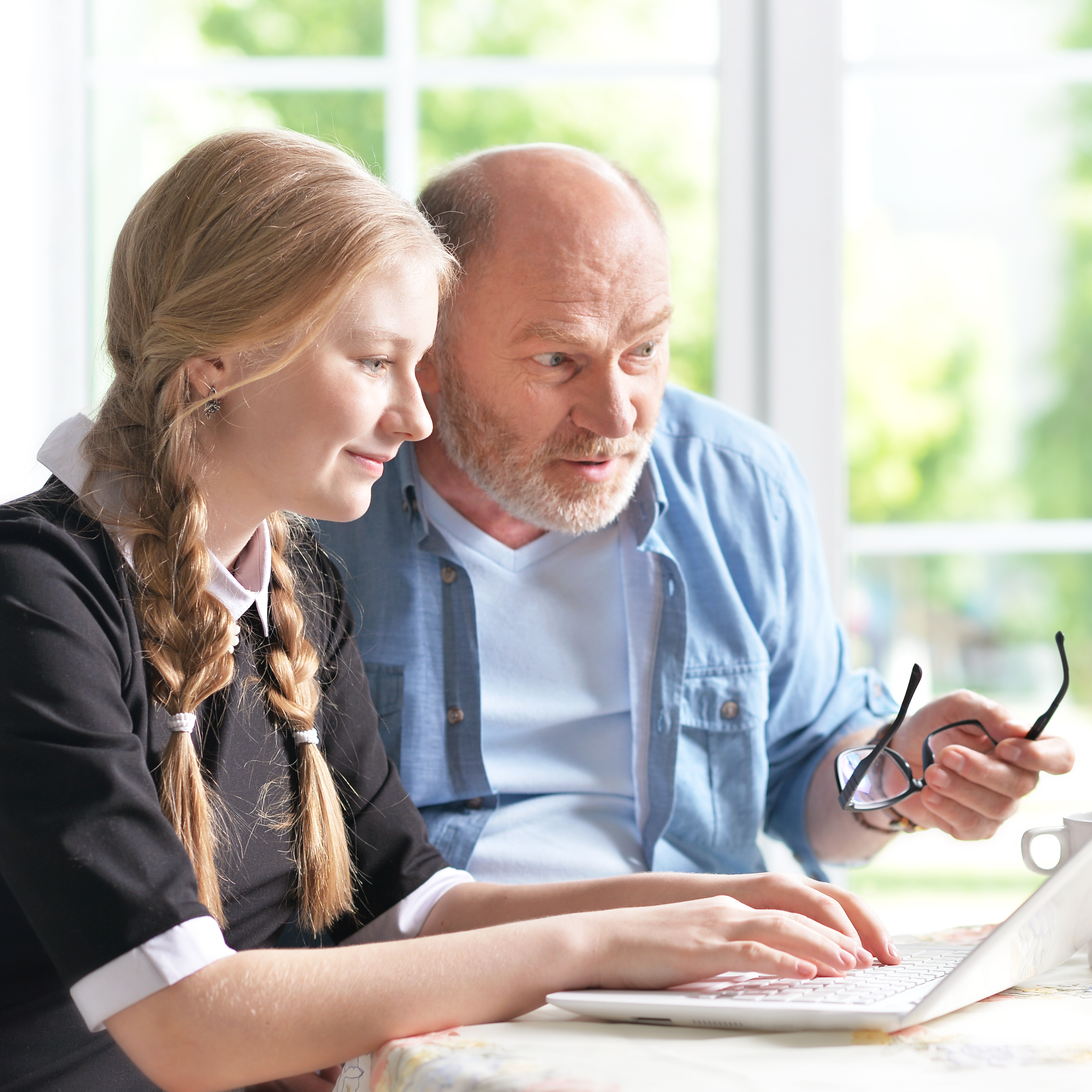 A grandfather sits with his granddaughter to go over her university application.