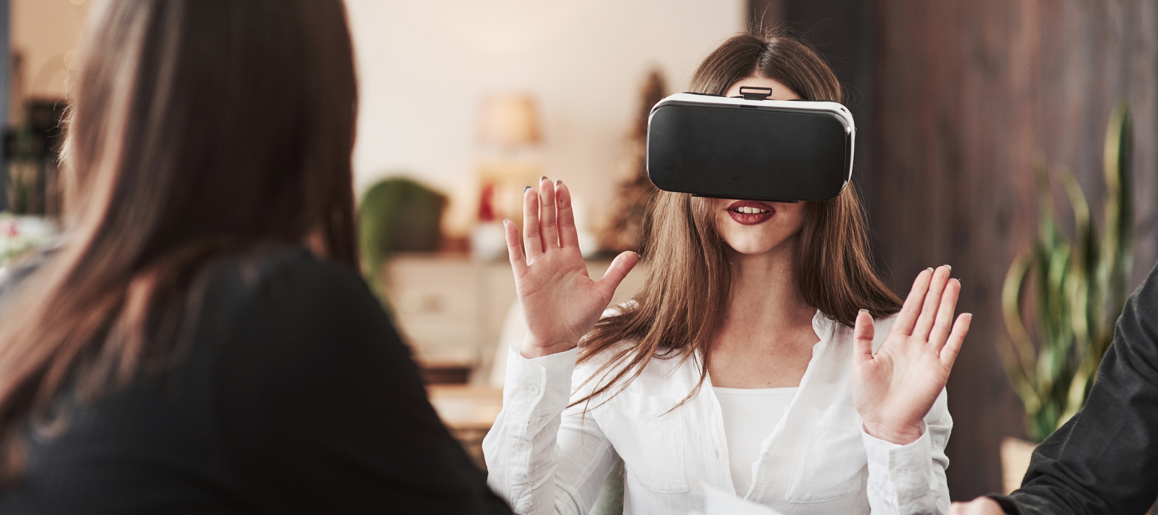 n indoor shot features a young woman with long brown hair wearing a virtual reality headset