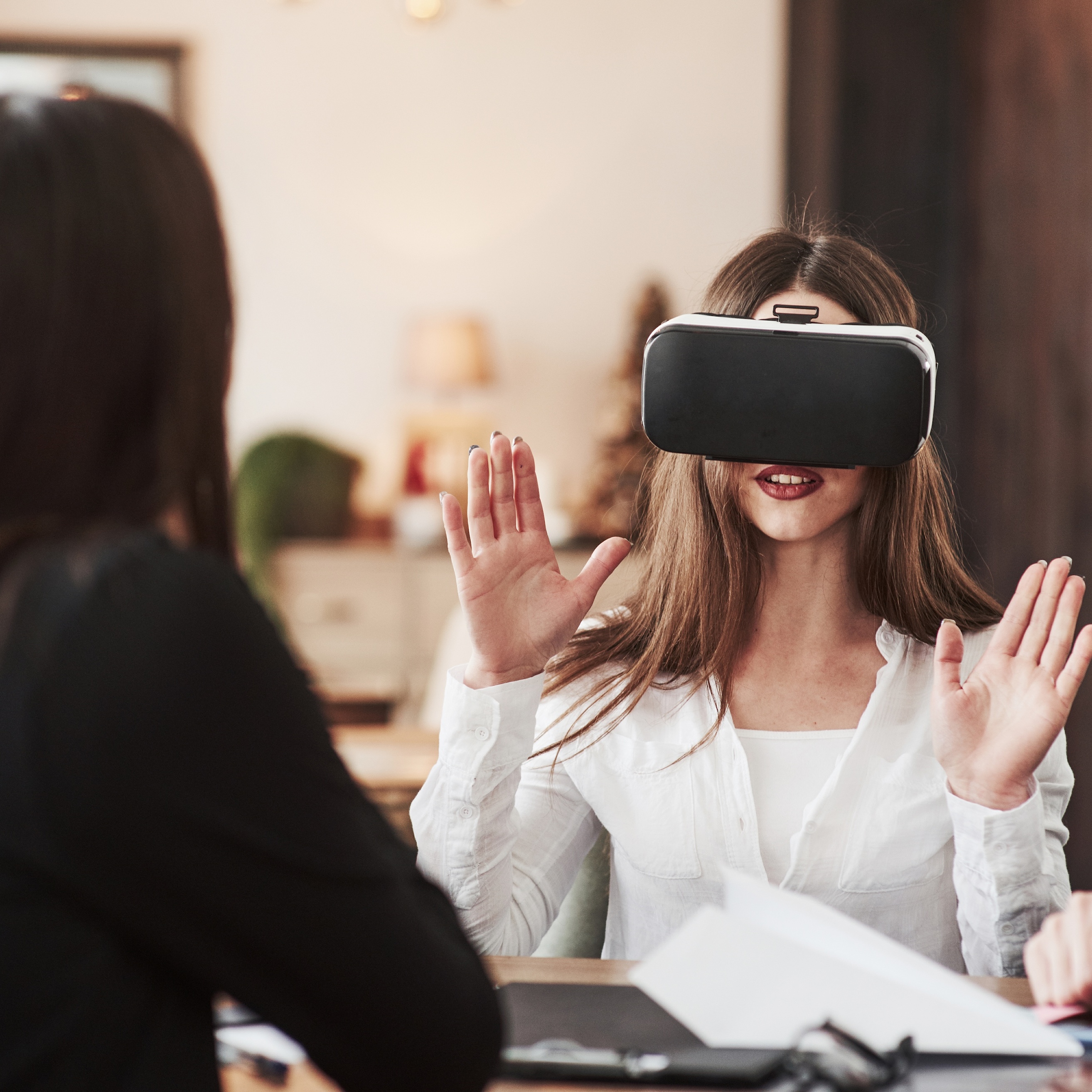 n indoor shot features a young woman with long brown hair wearing a virtual reality headset