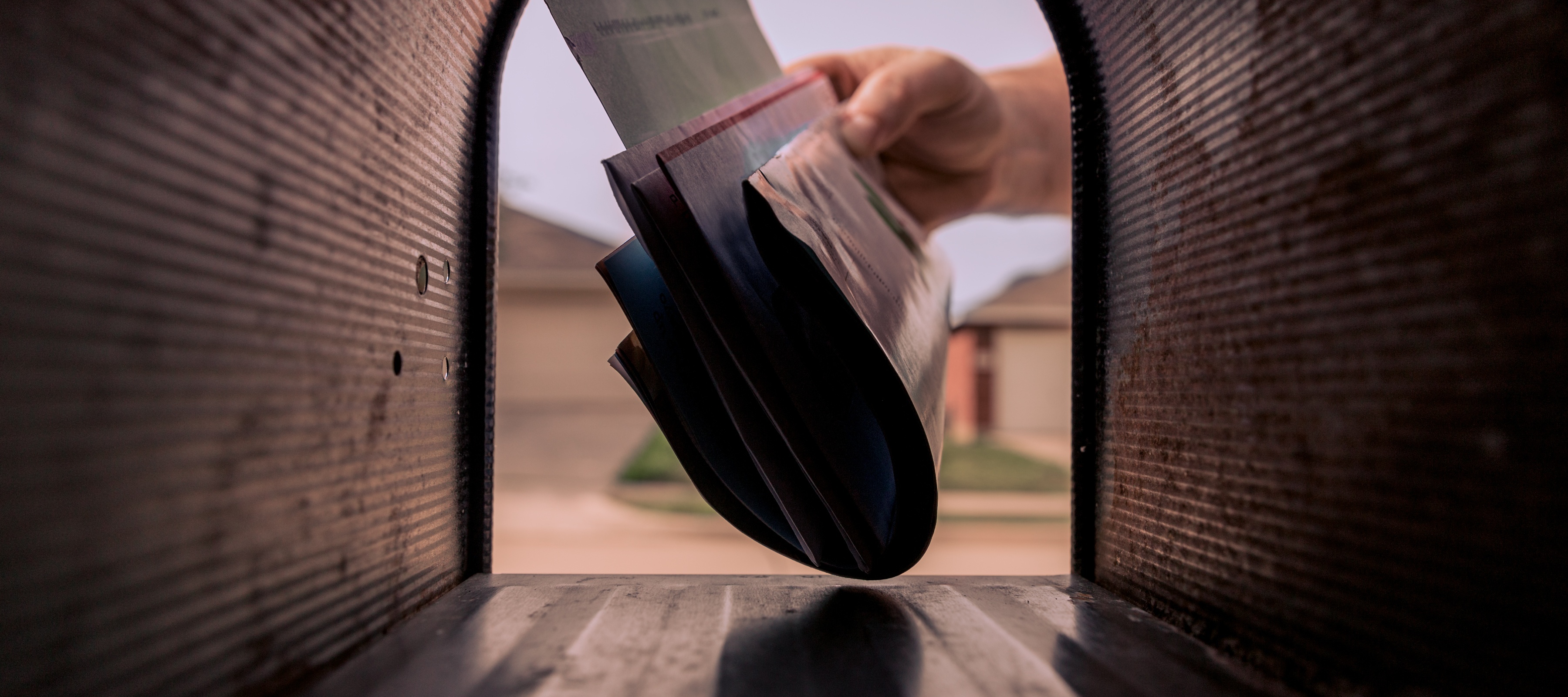 A hand getting mail out of their mailbox.