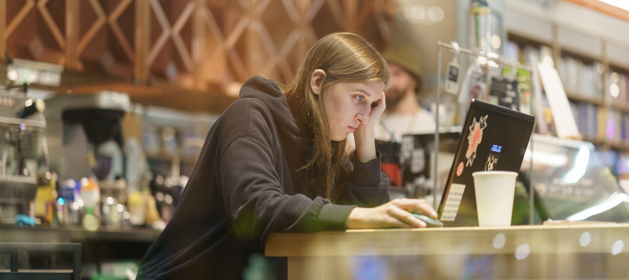 Young woman sitting in the cafe. She works, read something on the laptop screen