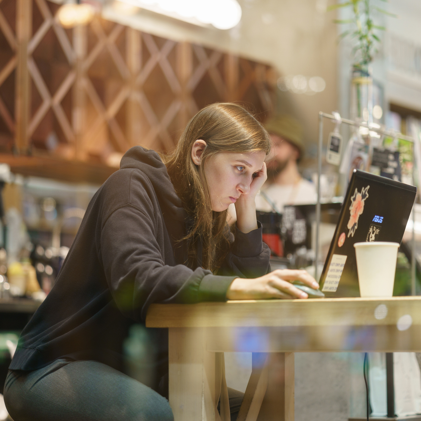 Young woman sitting in the cafe. She works, read something on the laptop screen
