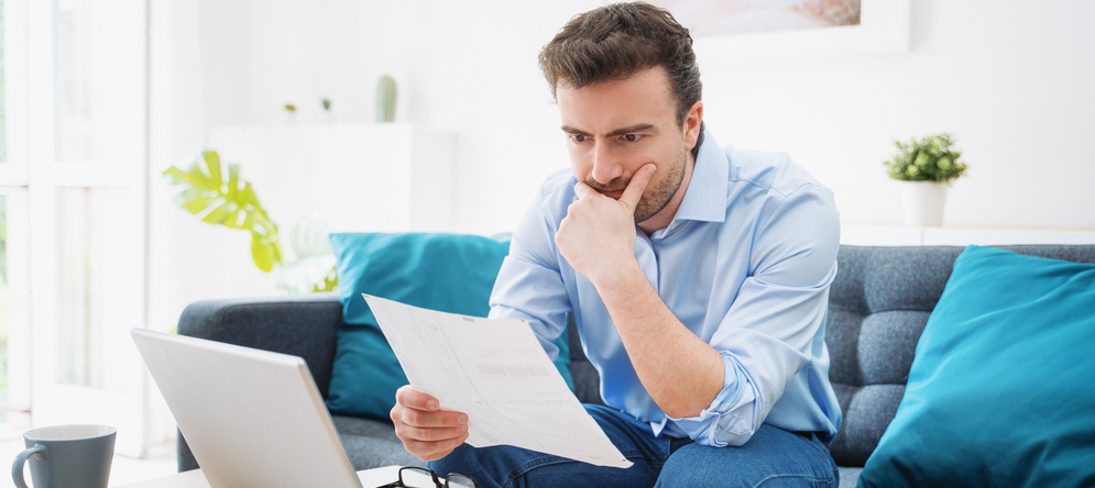 Man looks at a sheet of paper, wondering if he should pay off his debts.