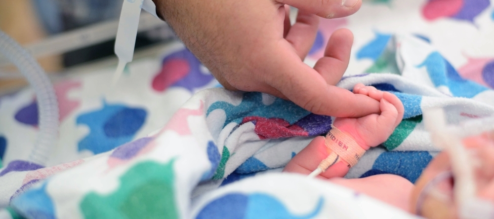 A photo of a parent holding their baby's hand