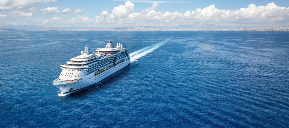 Aerial front view of a generic cruise ship sailing with speed over calm ocean.
