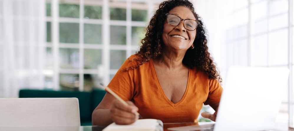 Black woman happily planning her retirement from the comfort of her own home.