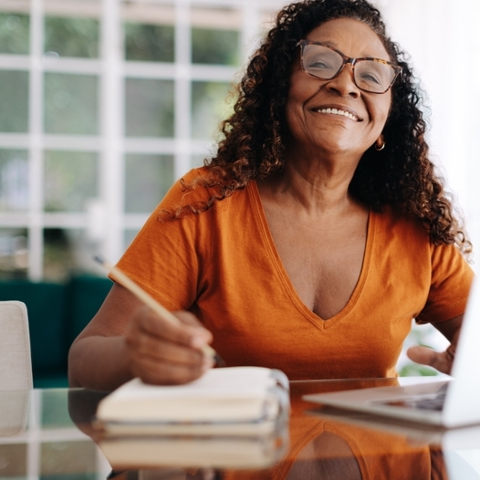 Black woman happily planning her retirement from the comfort of her own home.