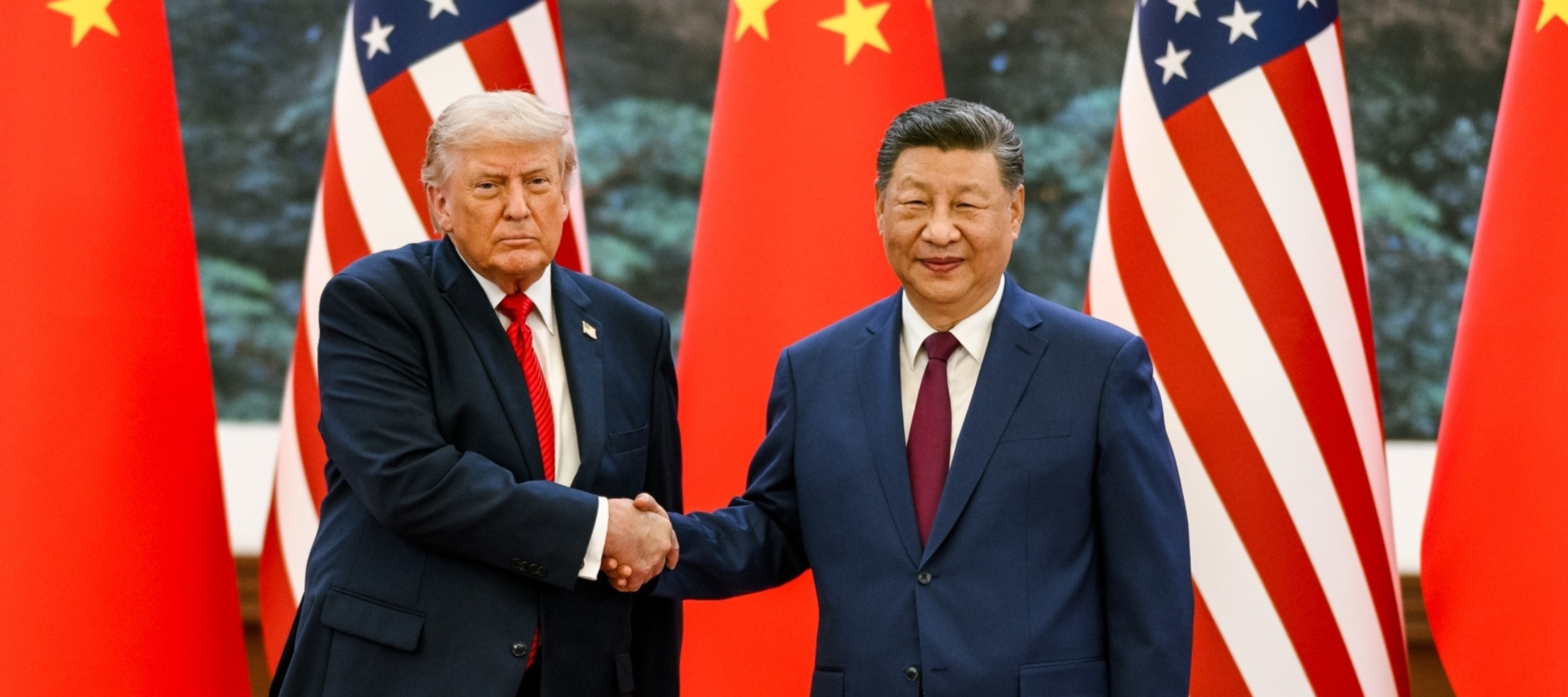 Xi Jinping and Donald Trump shake hands in front of their countries' flags