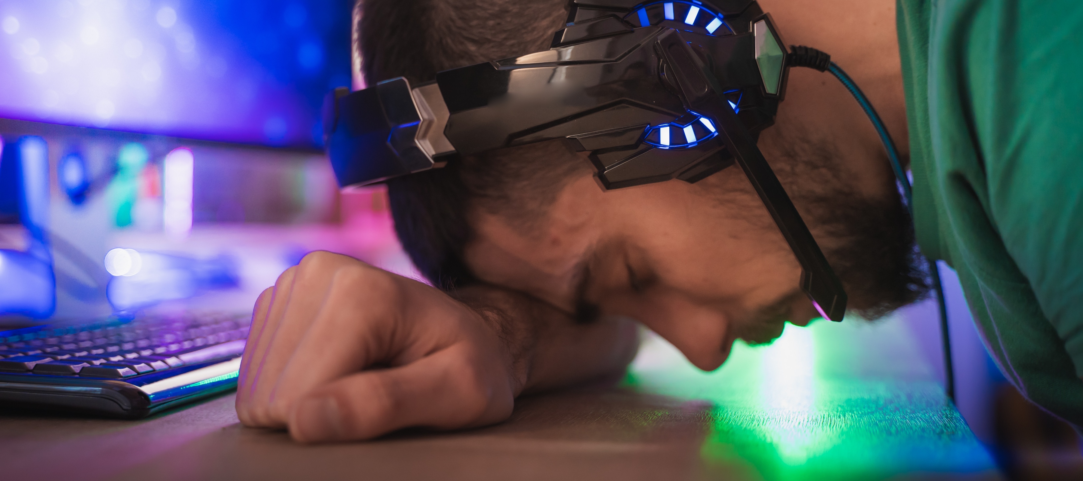 A man wearing a gaming headset slamming his head on a table in disappointment