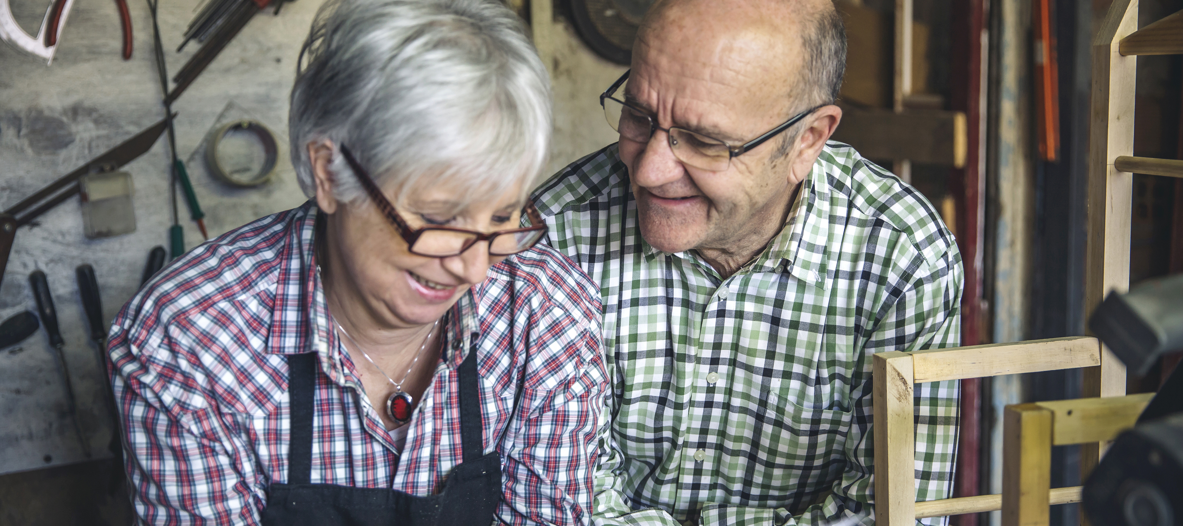 An elderly couple make plans in their workshop.
