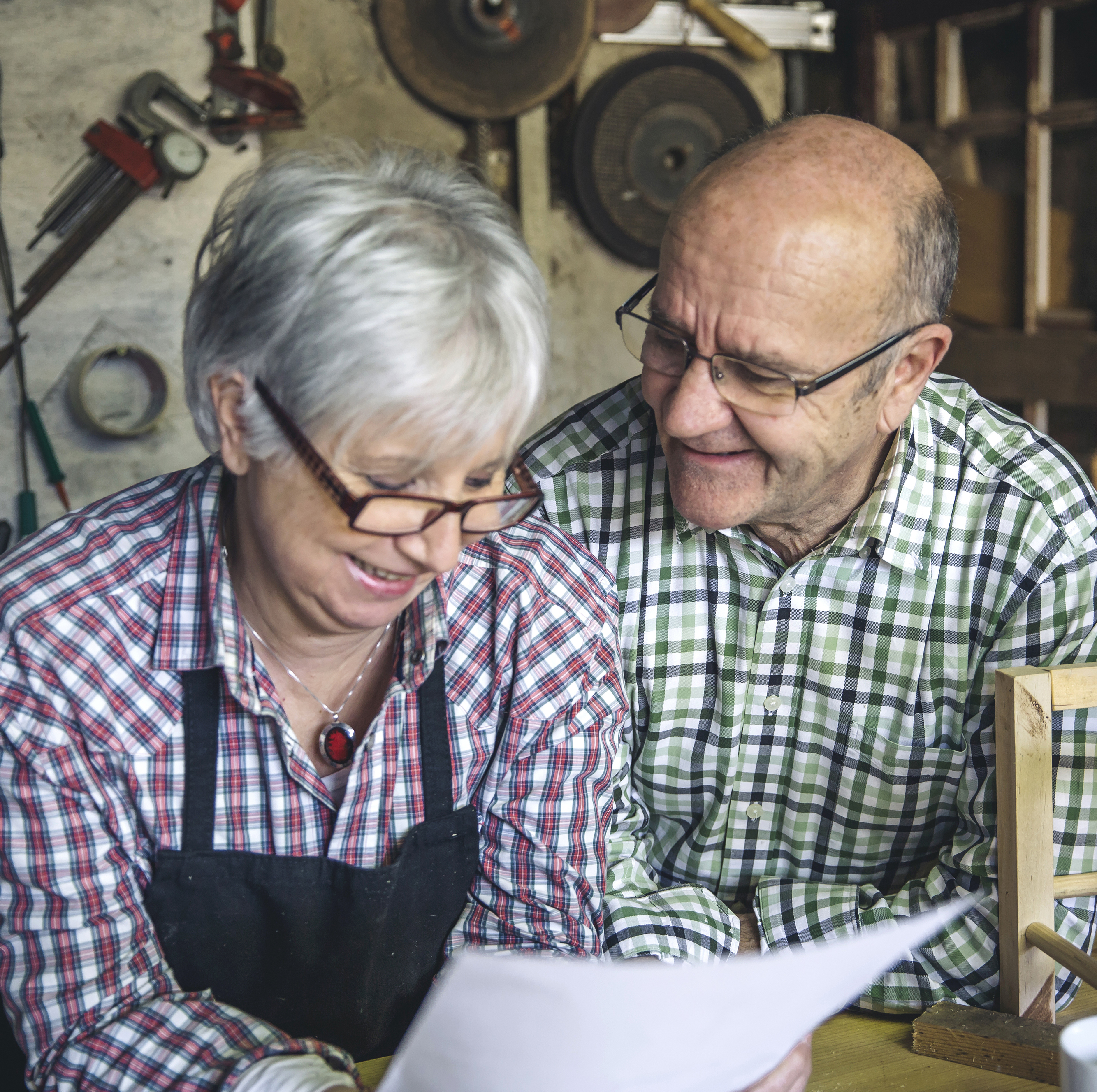 An elderly couple make plans in their workshop.