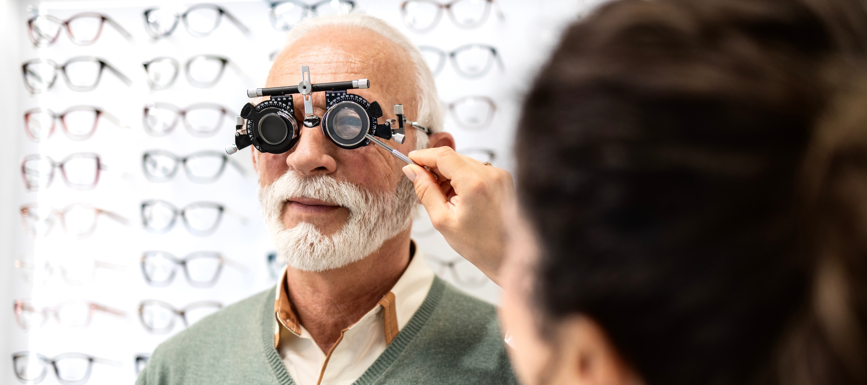 Professional ophthalmologist or optician testing senior man eyesight and diopter in eye clinic.