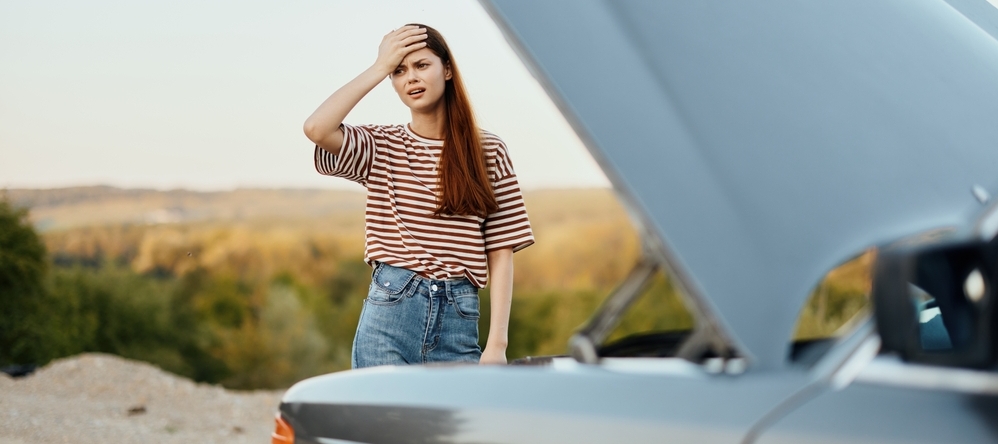Woman next to broken down car.