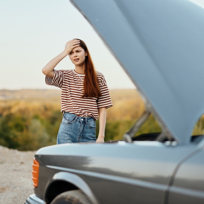 Woman next to broken down car.