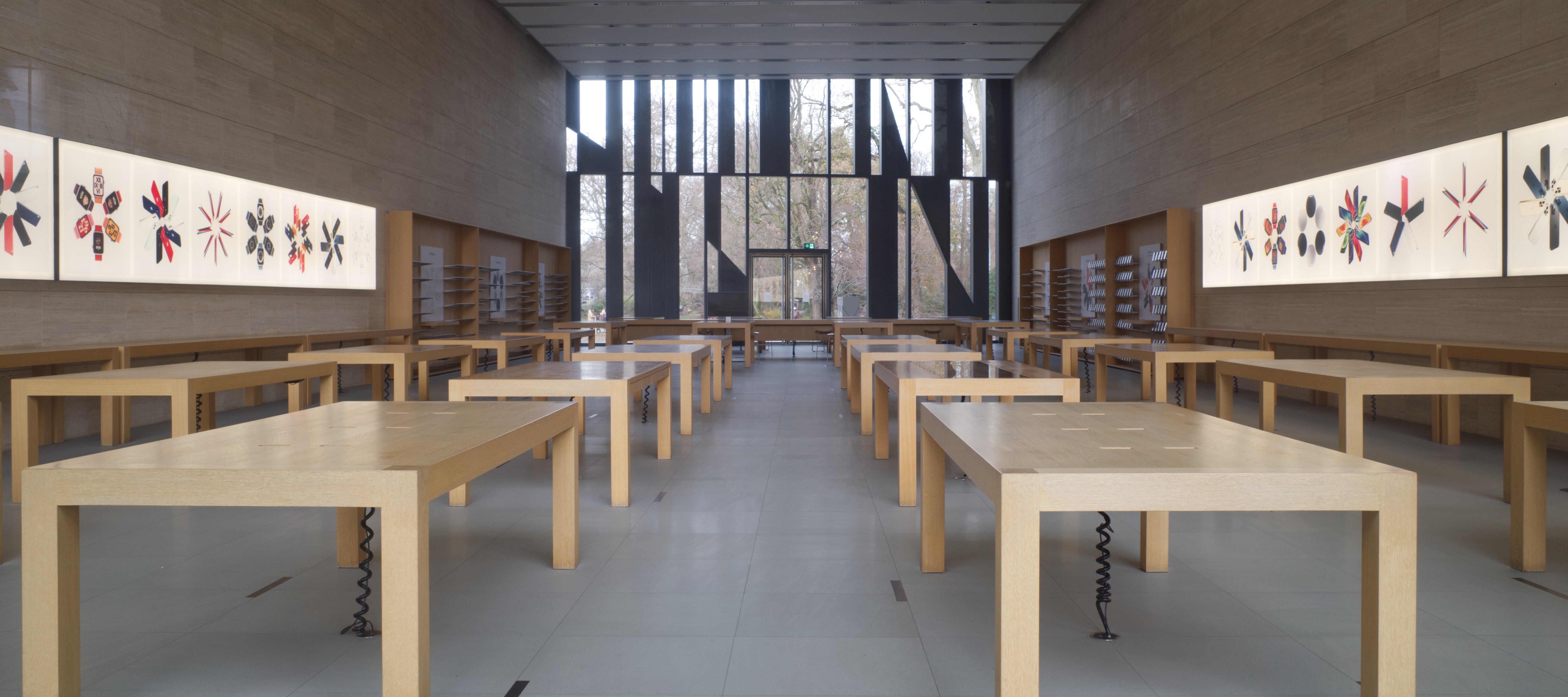 The interior view of an empty Apple Store location with no products on the tables or walls.